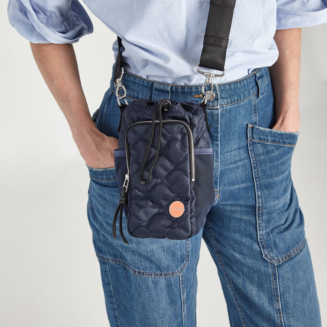 shortyLOVE bea sling bag in midnight; on model in jeans against grey background.