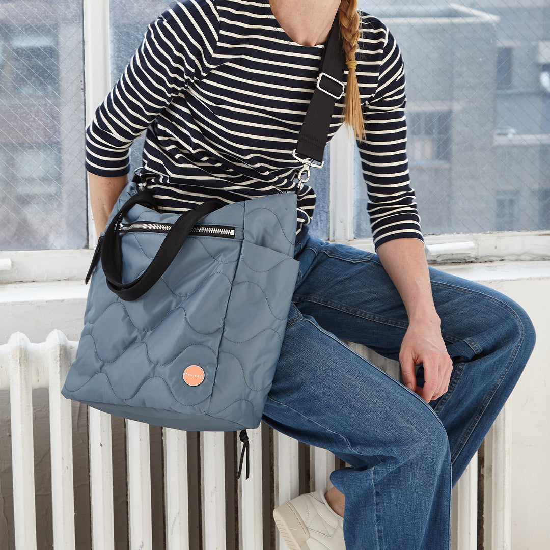 shortyLOVE ranger large tote bag in steel blue; on model in striped shirt and jeans against white background.