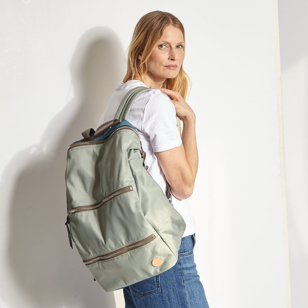 Woman wearing a slate/teal boxer backpack against a white background