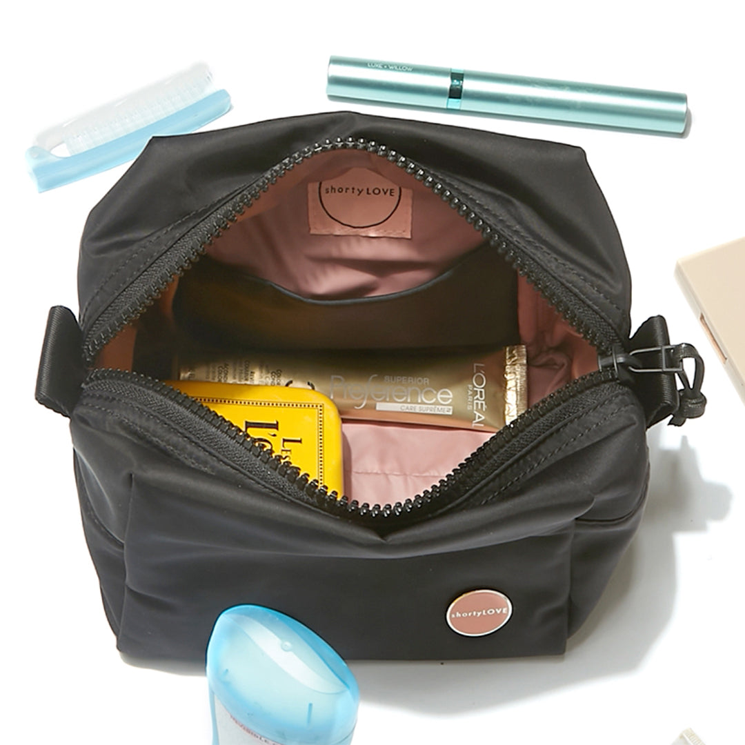 Black cosmetic travel bag with cosmetic items on a white background