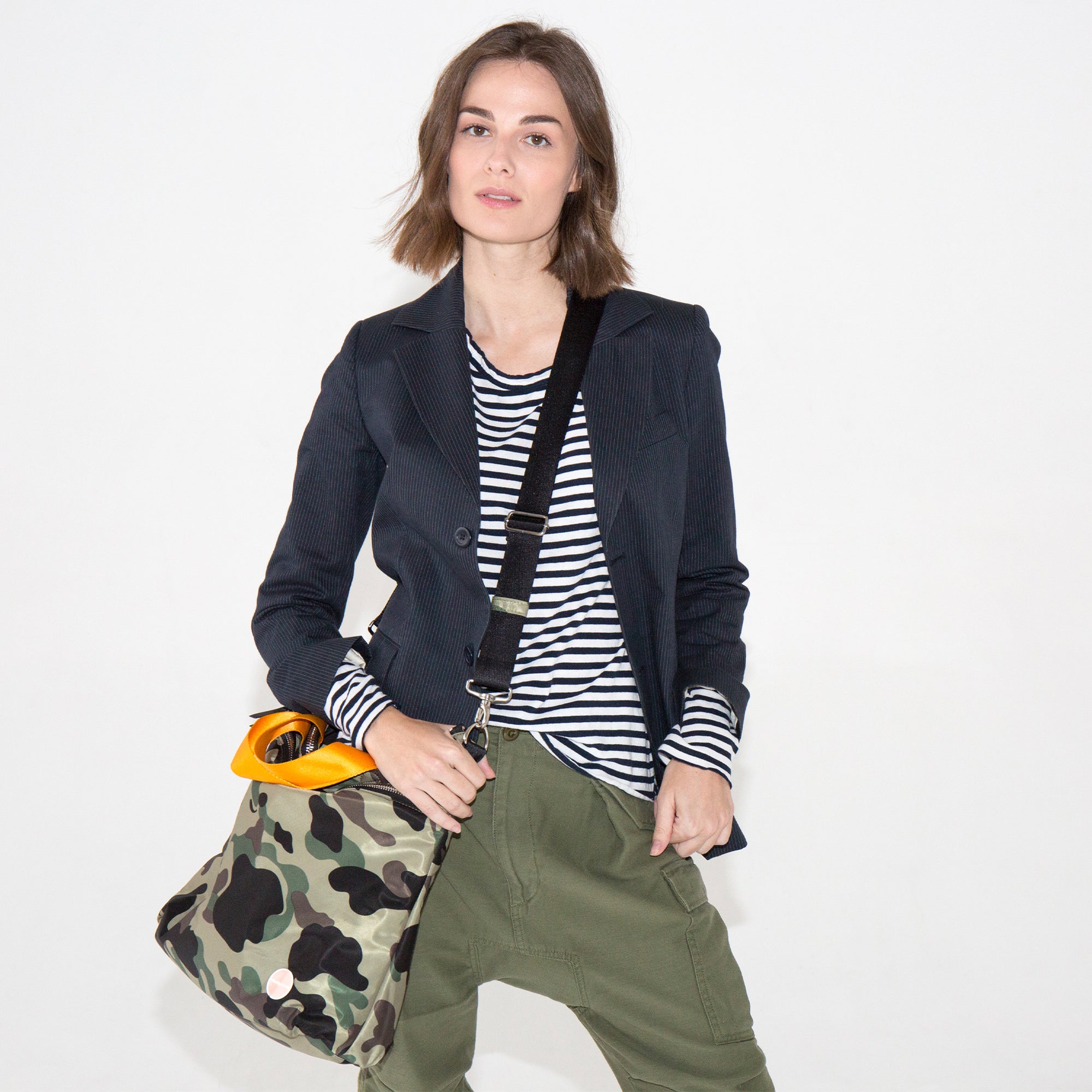 model in navy blazer and green cargo ants with camo wonder crossbody bag
