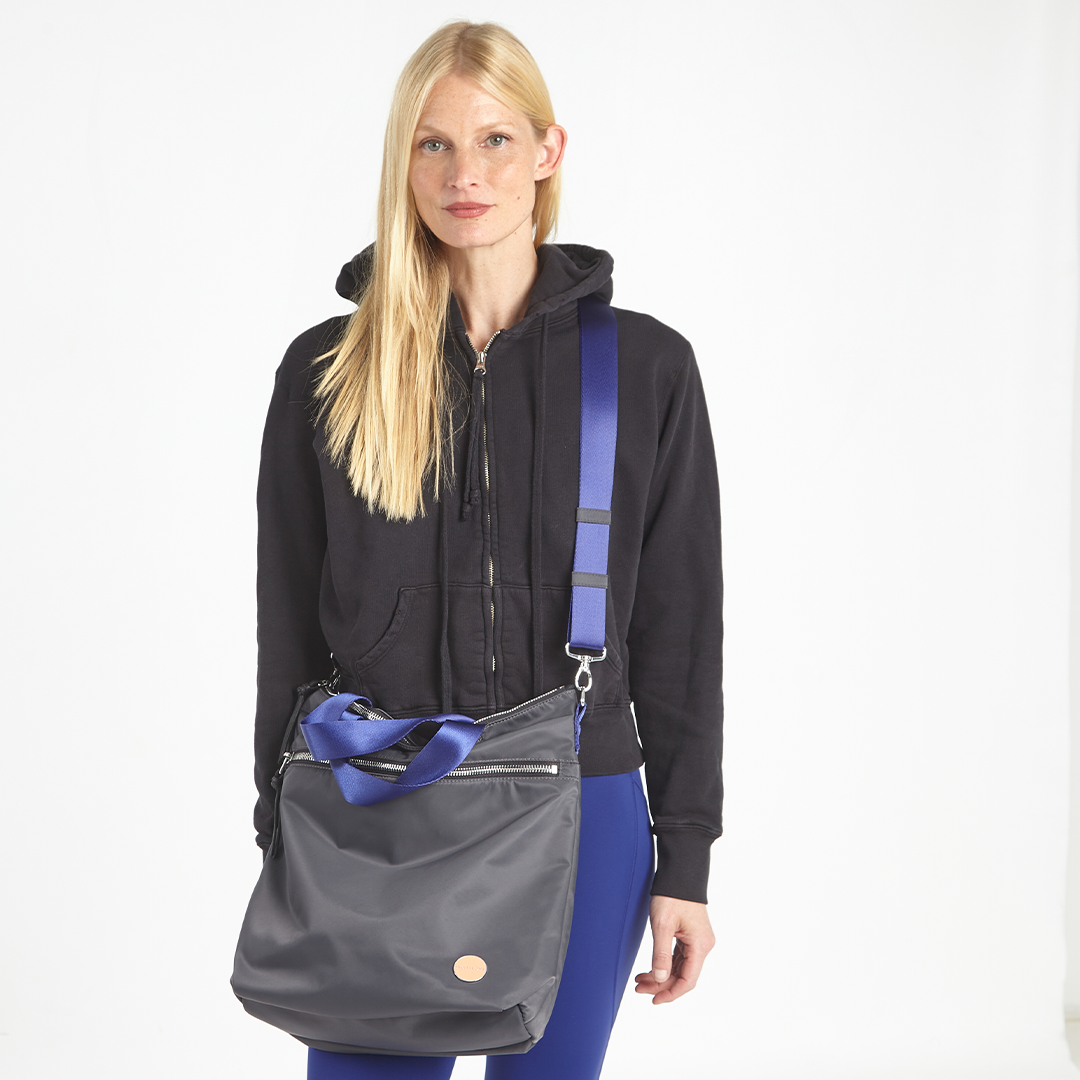 shortyLOVE wonder large crossbody/messenger bag in charcoal; on model in workout clothing against white background.