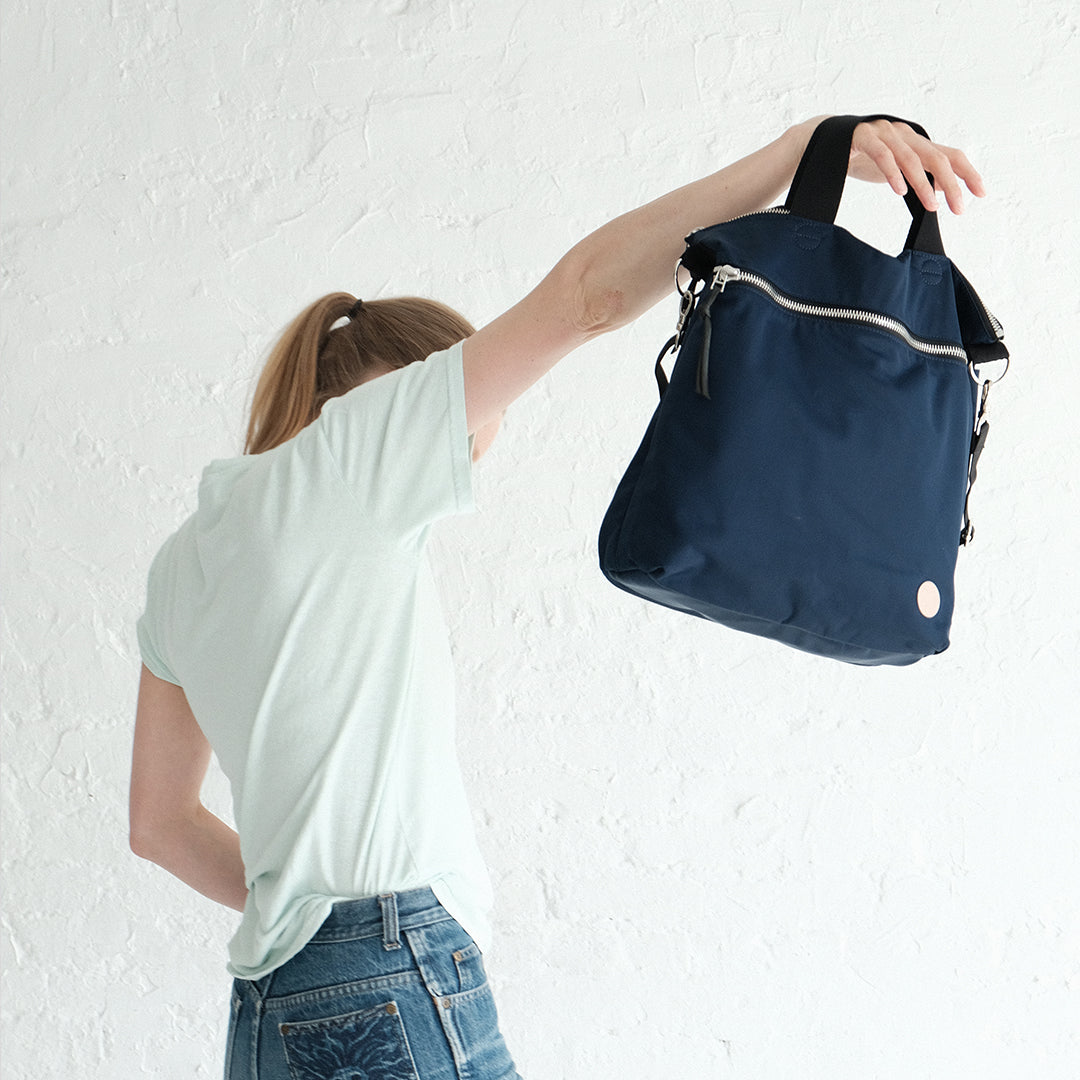 Person holding up a navy wonder crossbody bag against a white background