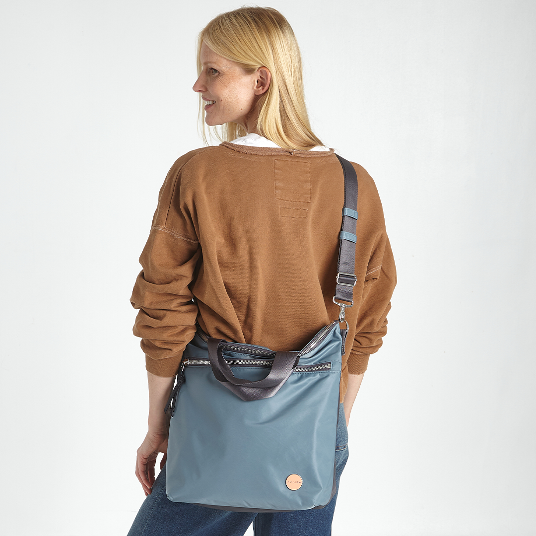 shortyLOVE wonder large crossbody/messenger bag in steel blue/charcoal; worn crossbody by model in jeans and brown top against white background.