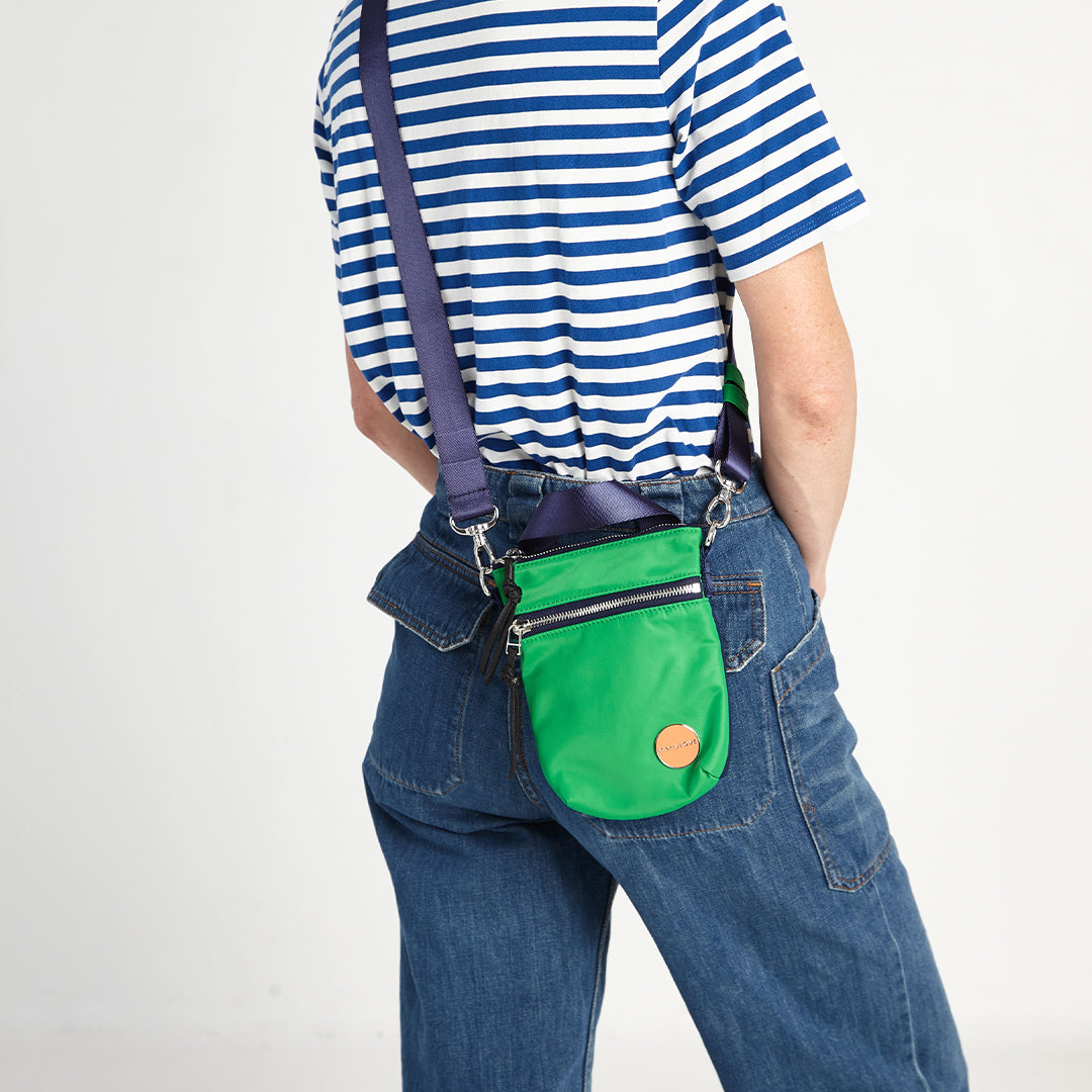 shortyLOVE shorthand small crossbody bag in grass green/navy; on model in striped top and jeans against white background.