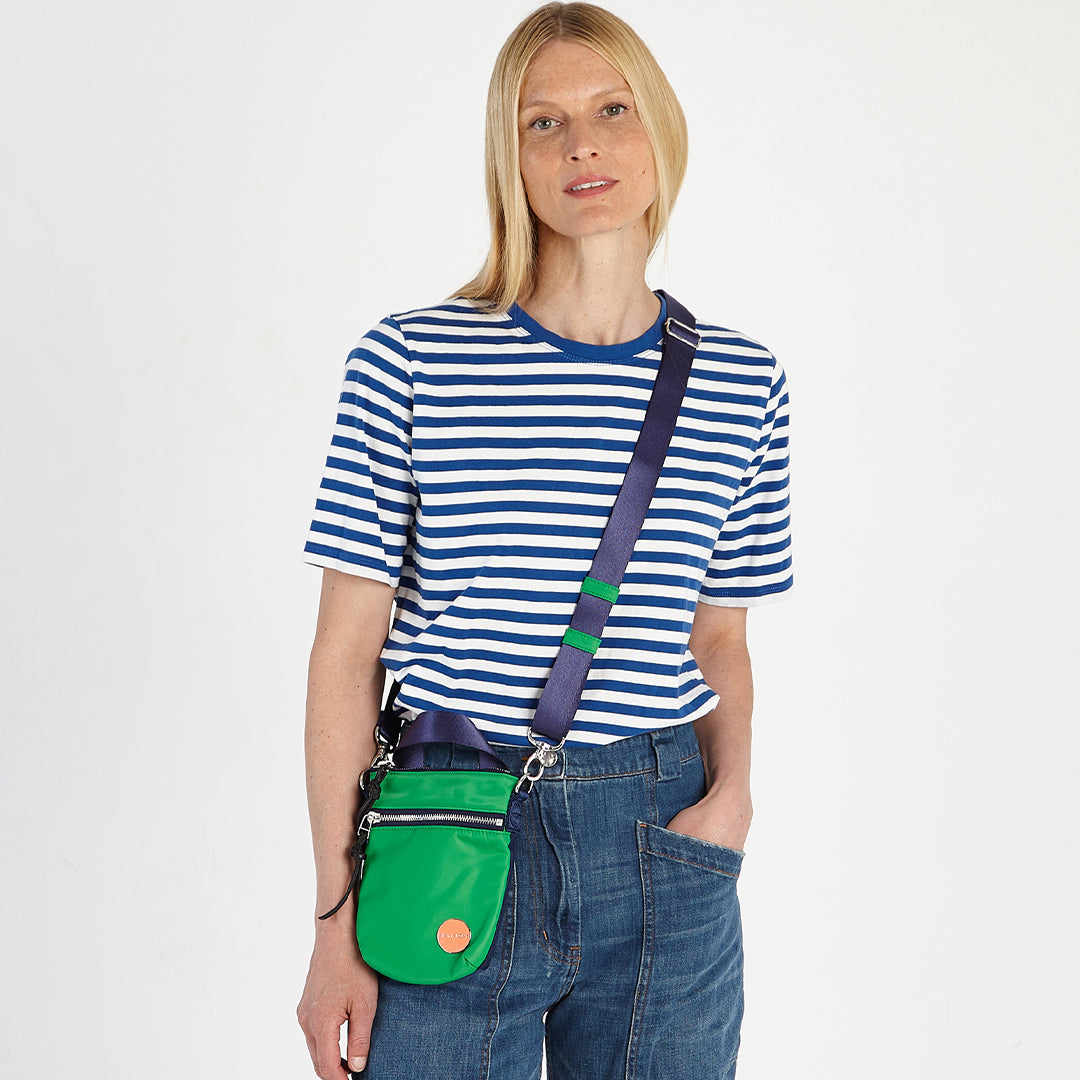 shortyLOVE shorthand small crossbody bag in grass green/navy; on model in striped top and jeans against white background.