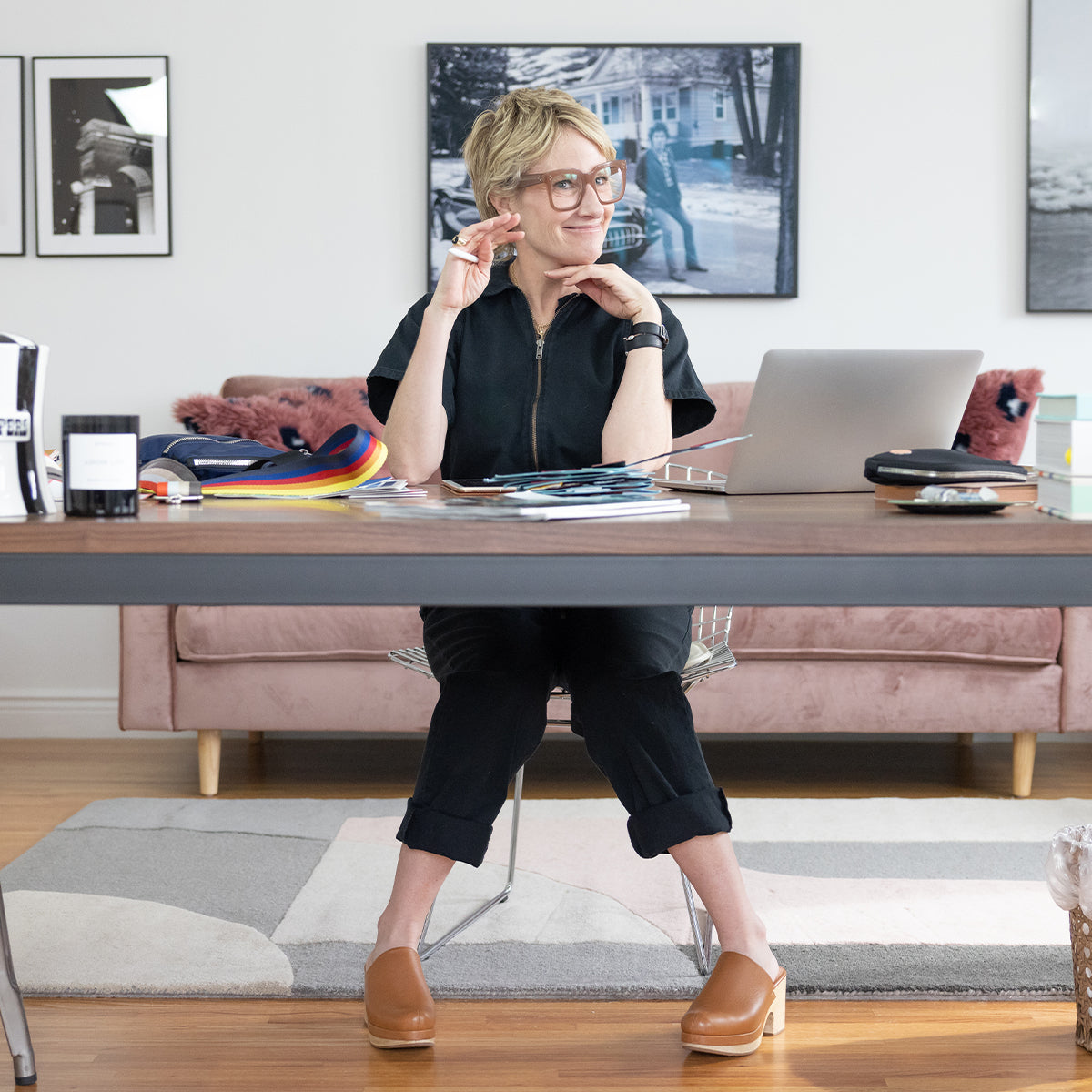 sloane sitting at a desk with a laptop, books, and a phone in a home office setting.