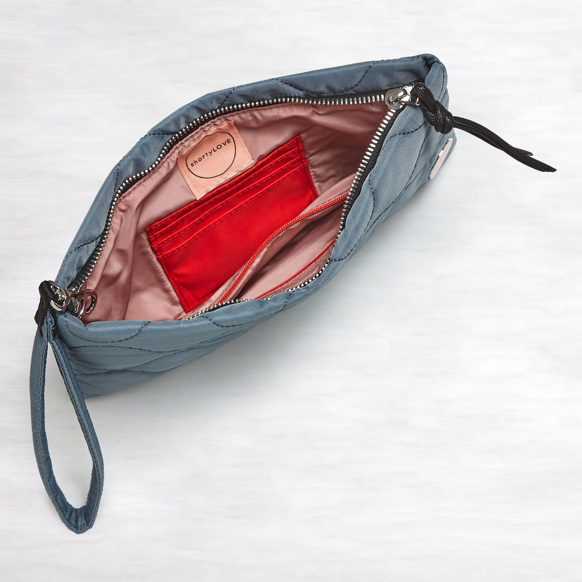 shortyLOVE cleo wristlet clutch in steel blue; top-down view showing interior blush lining against white background.