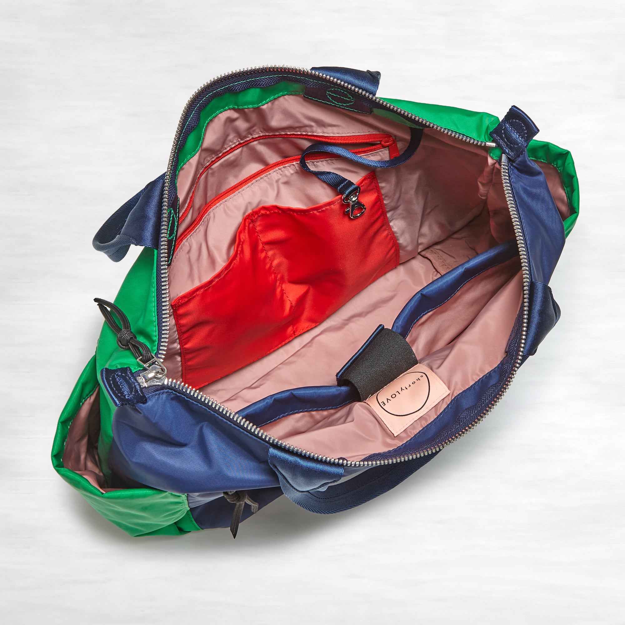 shortyLOVE tillie tote bag in grass green/navy; top-down view showing interior blush/red lining against white background.