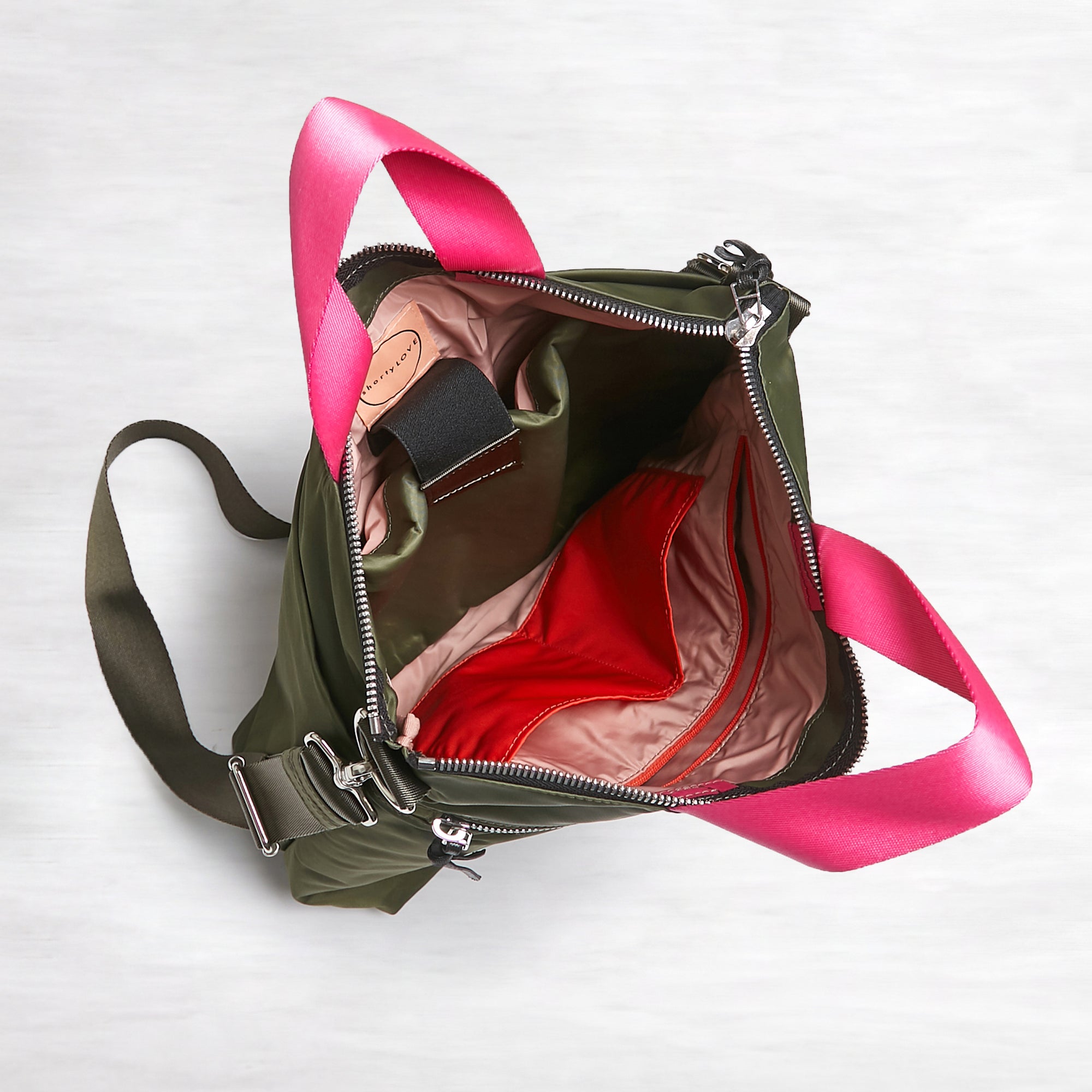shortyLOVE wonder large crossbody/messenger bag in army green; top-down view showing interior pink lining against white background.