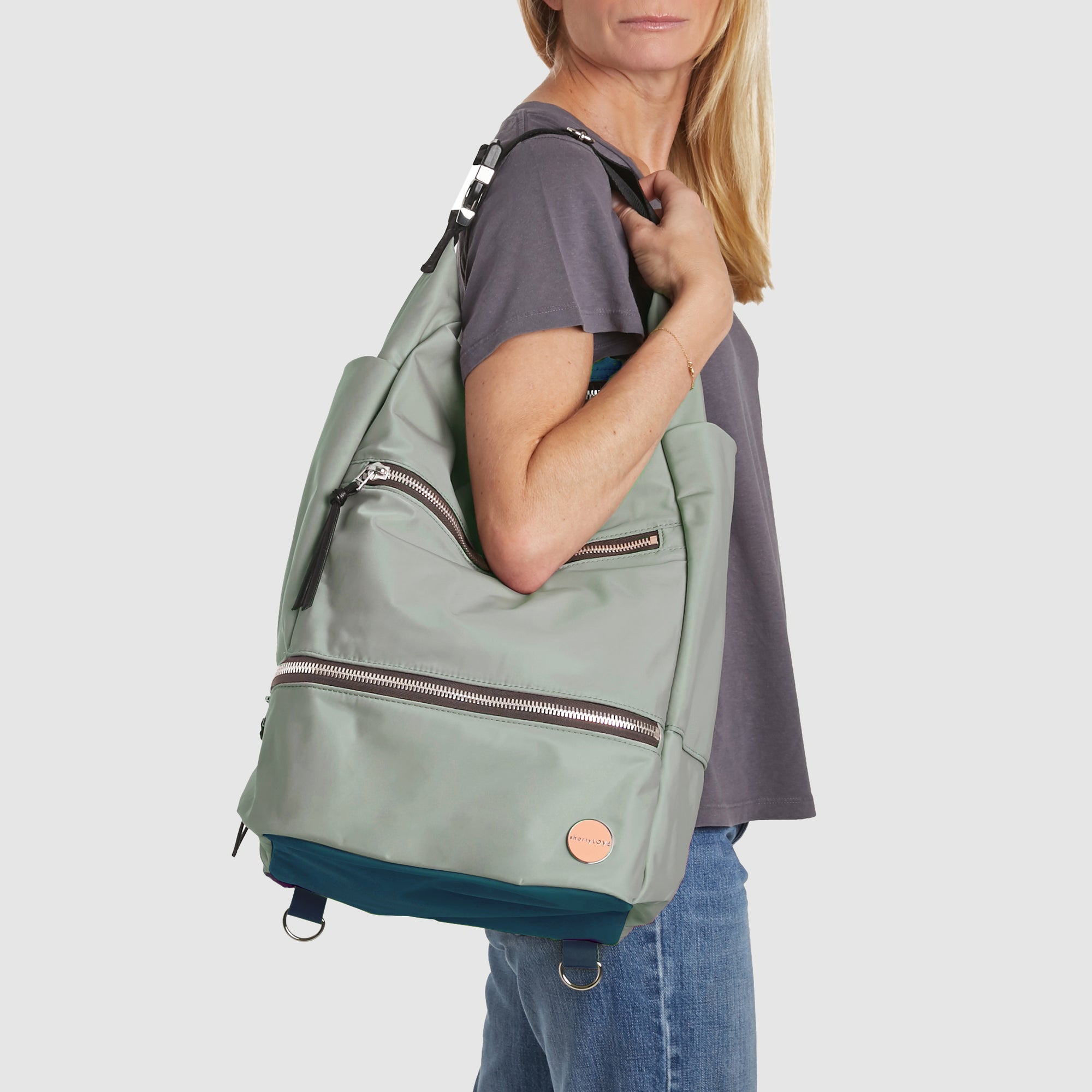 shortyLOVE boxer backpack in slate/teal; on model over shoulder in grey t-shirt and jeans against white background.
