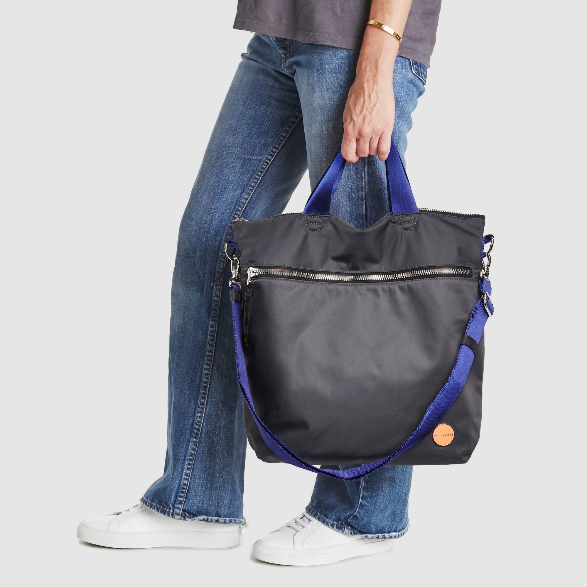 shortyLOVE wonder large crossbody/messenger bag in charcoal; hand held by model in jeans against white background.