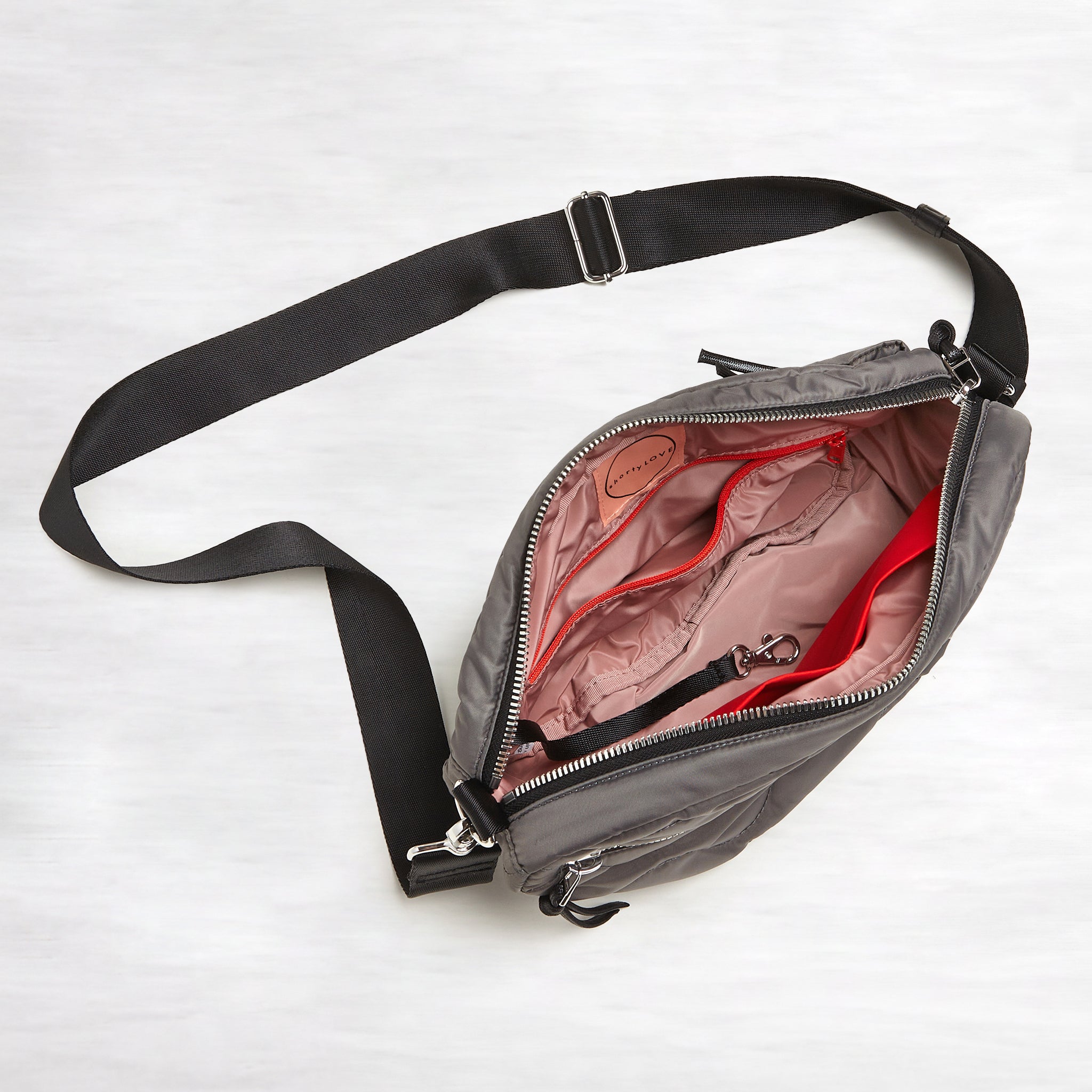 shortyLOVE cruiser medium crossbody bag in pewter; top-down view showing interior blush lining against white background.