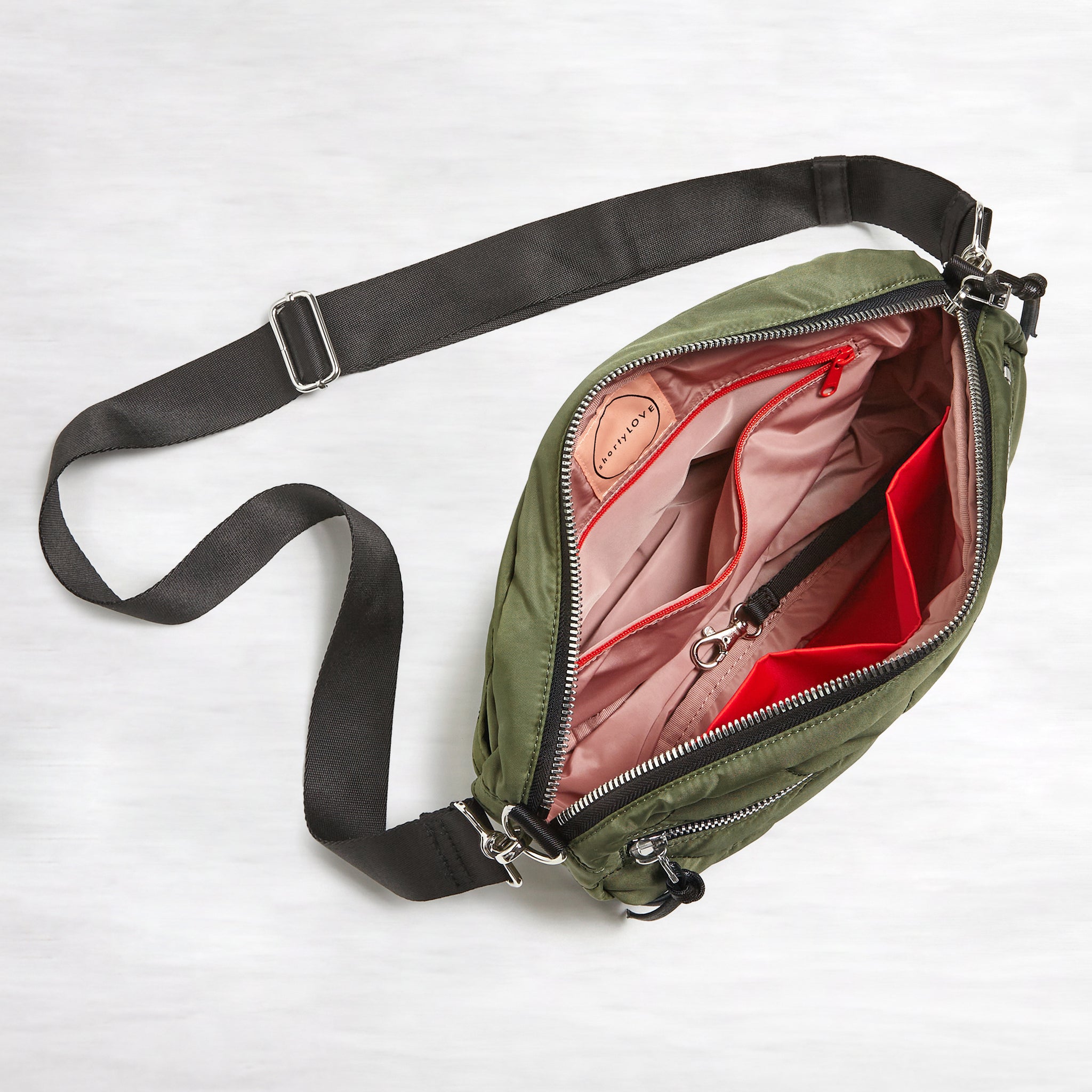 shortyLOVE cruiser medium crossbody bag in sage; top-down view showing interior blush lining against white background.