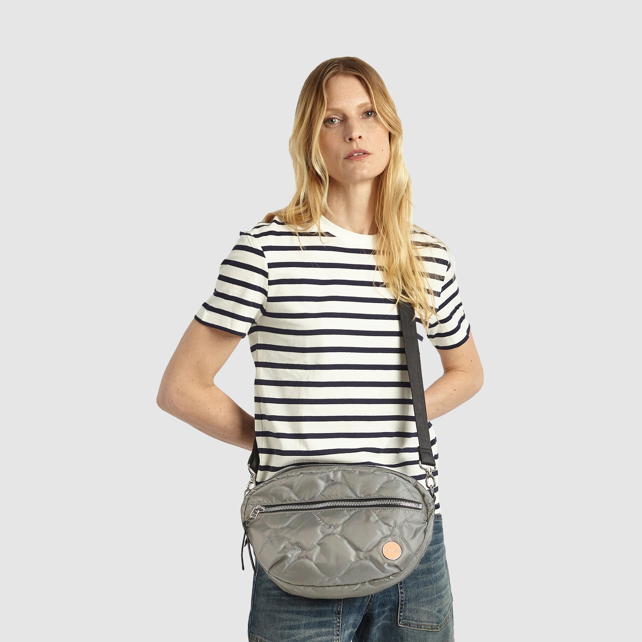 shortyLOVE cruiser medium crossbody bag in milky grey; on model in striped t-shirt and jeans against white background.