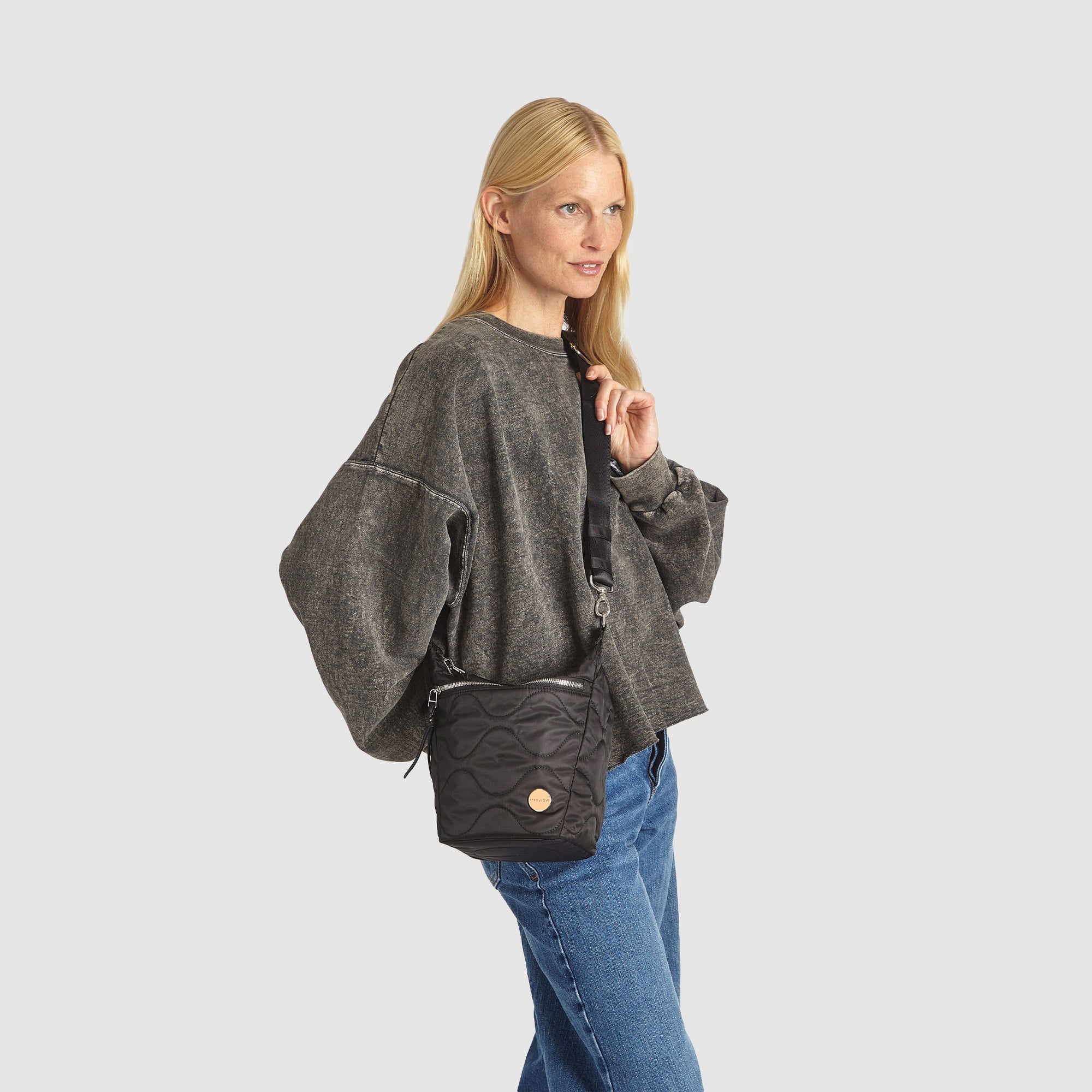 Woman with a black marcel quilted crossbody bag on her shoulder against a white background