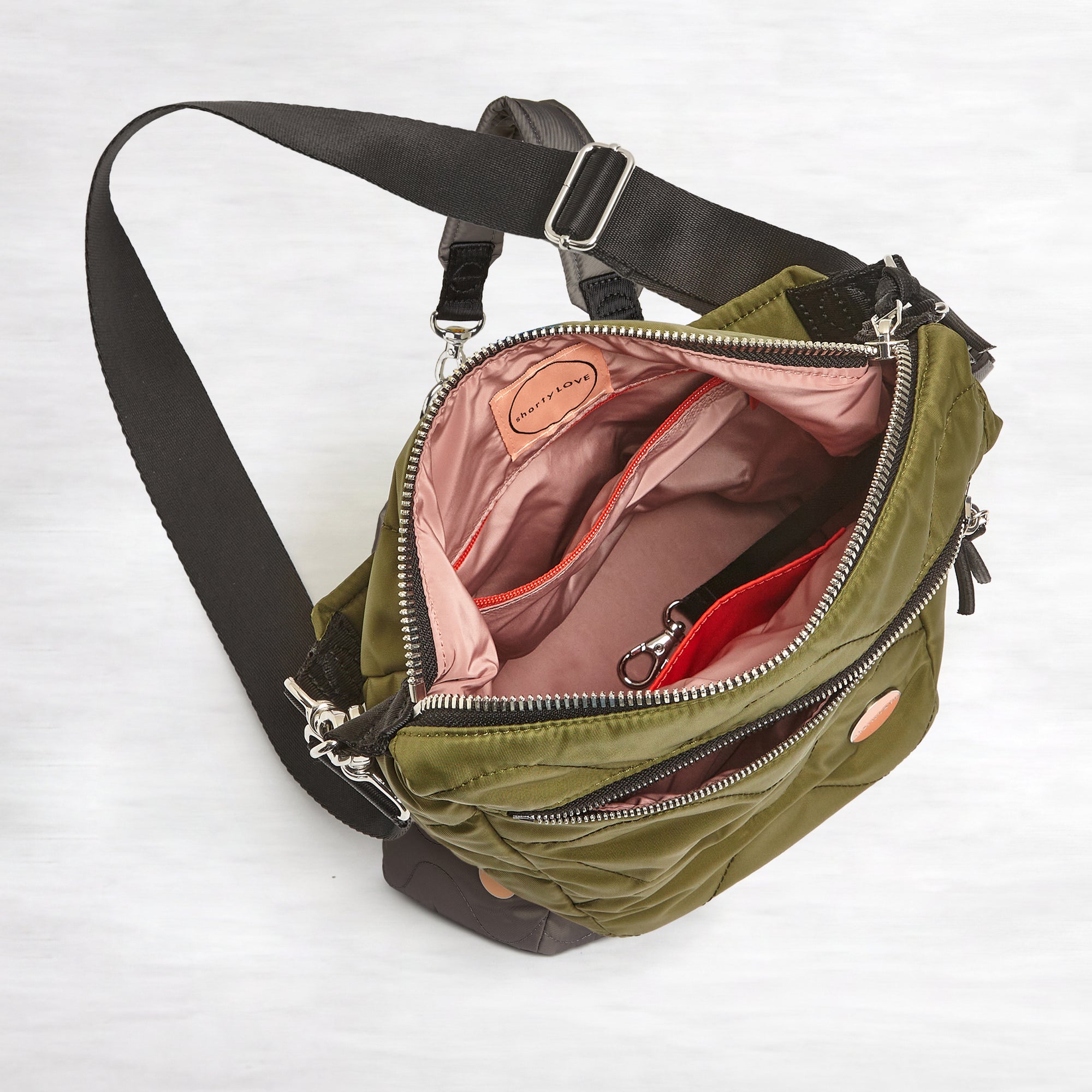 shortyLOVE marcel crossbody bucket bag in sage; top-down view showing interior blush lining against white background.