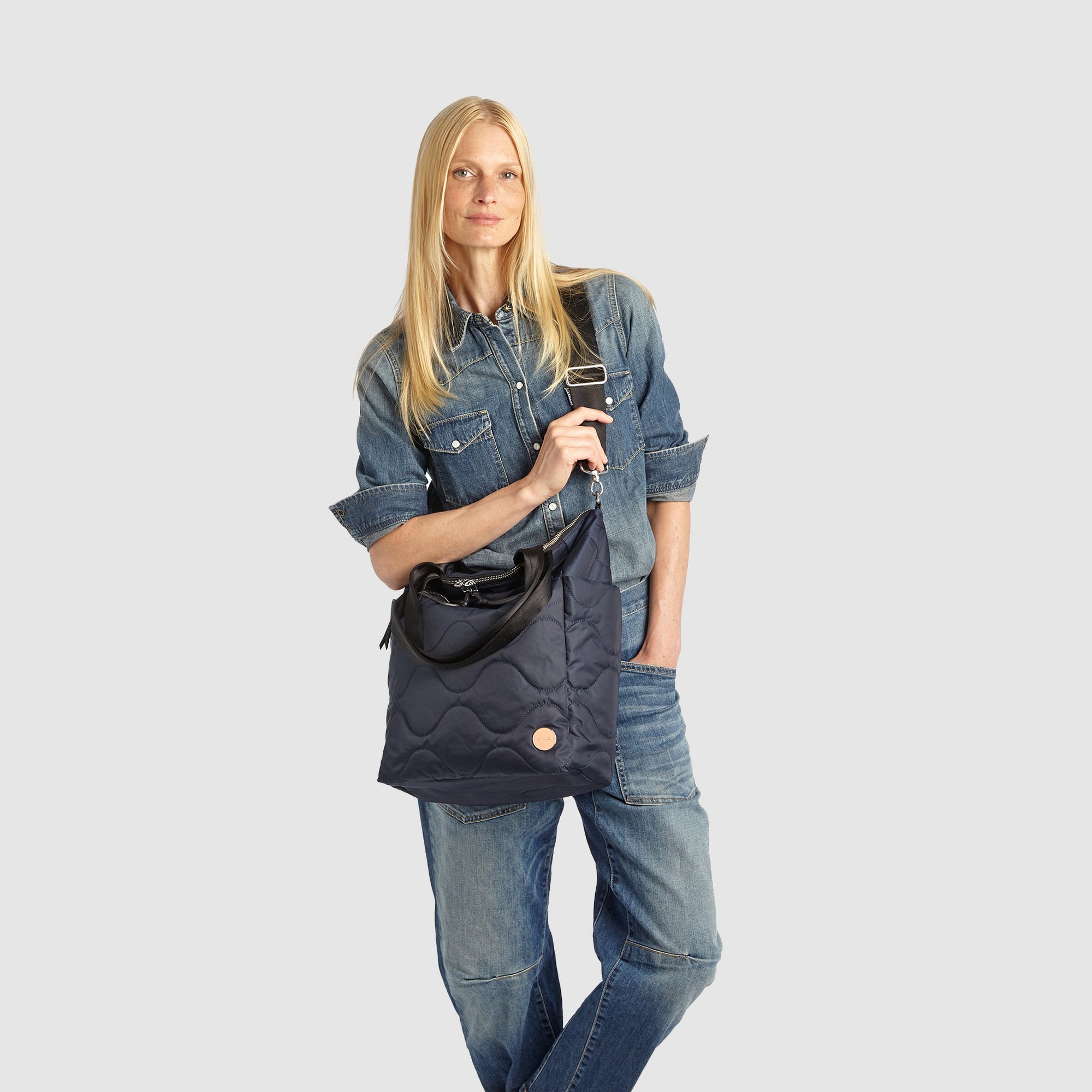 Woman holding a midnight blue ranger quilted handbag against a white background