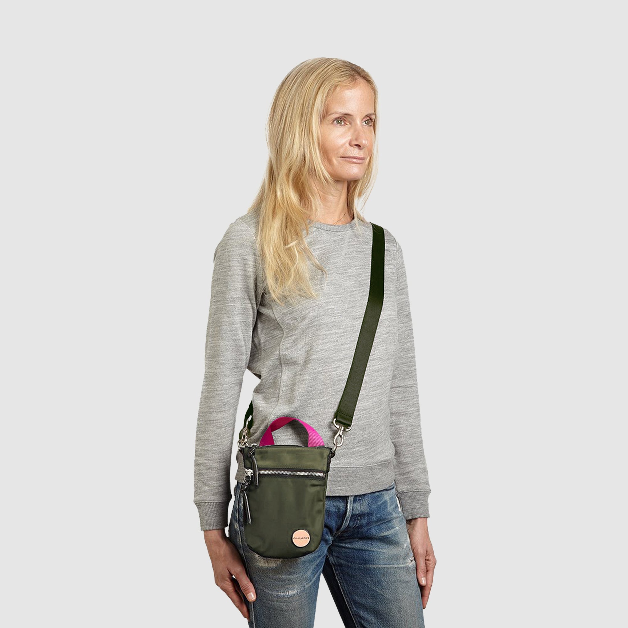 shortyLOVE shorthand crossbody phone bag in army green; on model in grey sweatshirt and jeans against white background.