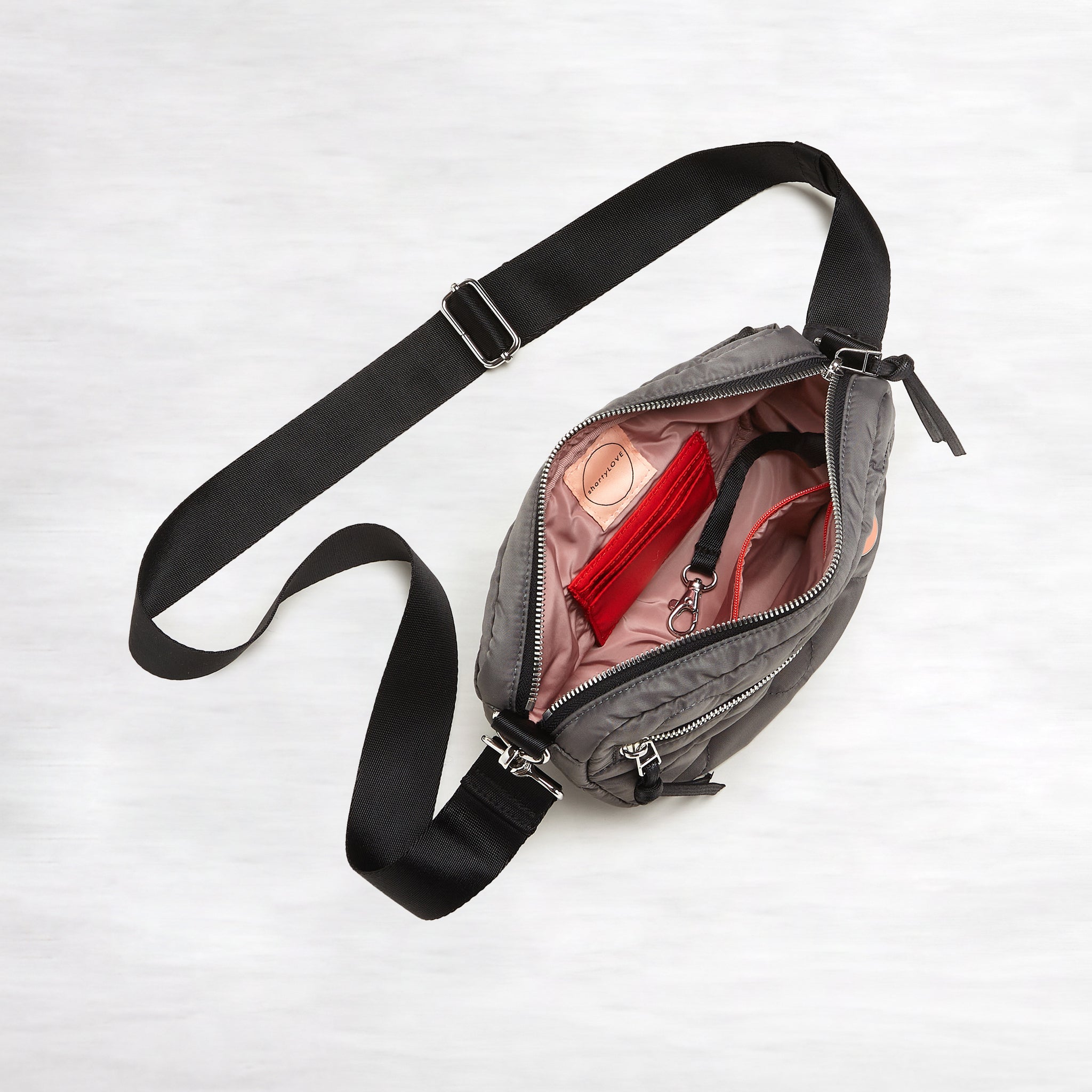 shortyLOVE small cruiser small crossbody bag in pewter; top-down view showing interior blush lining against white background.