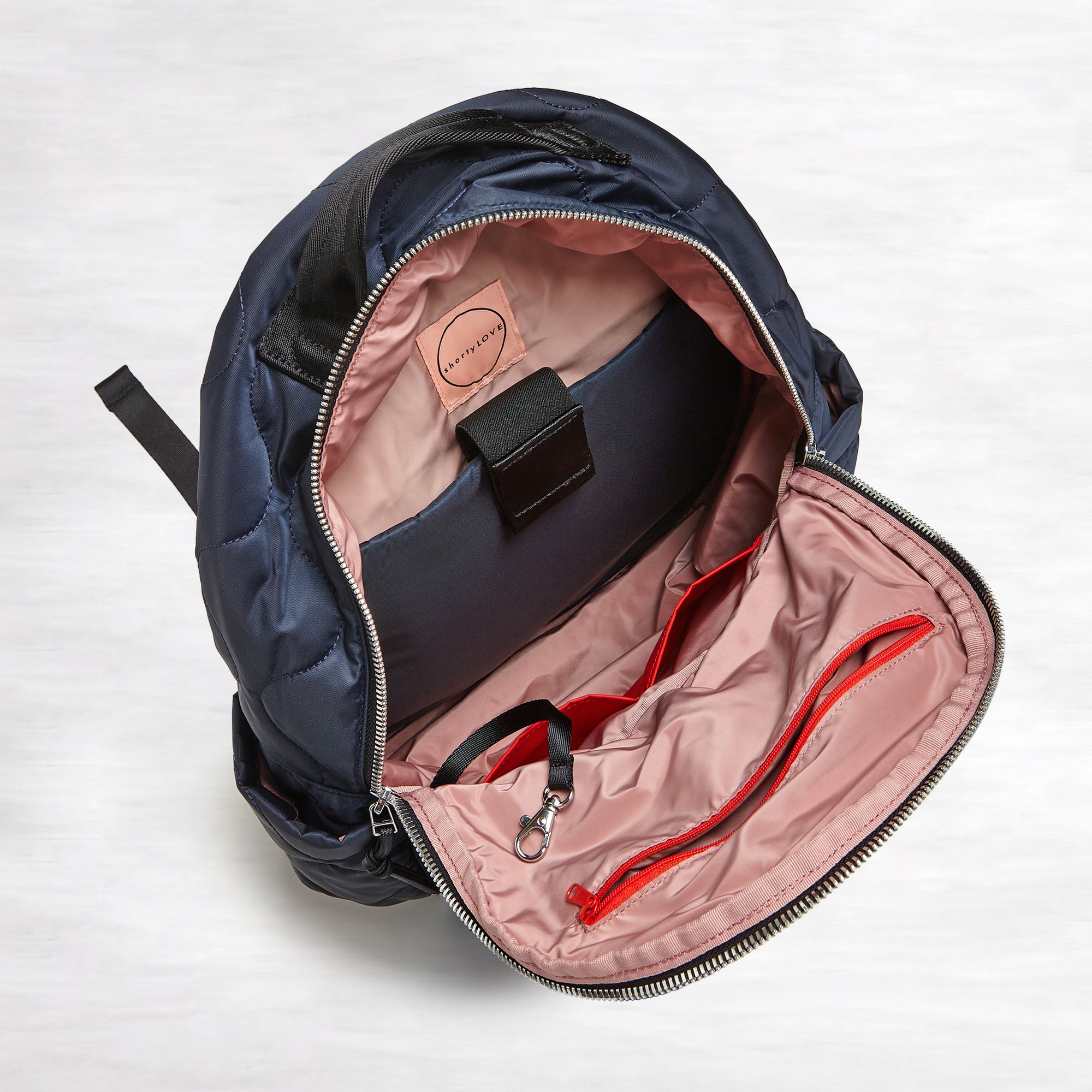shortyLOVE tate backpack in midnight; top-down view showing interior blush lining against white background.