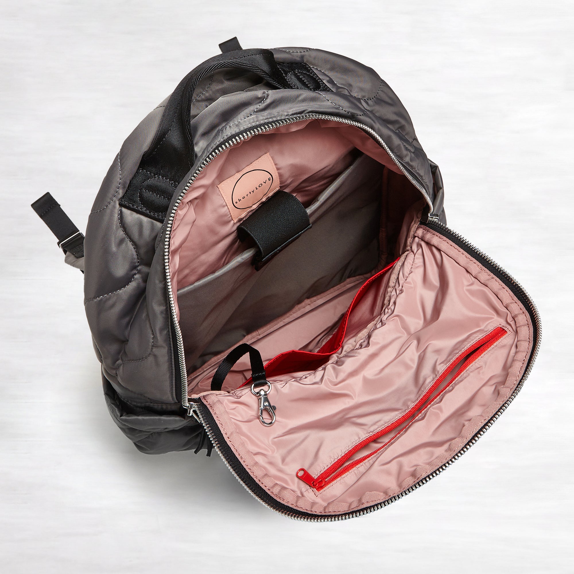 shortyLOVE tate backpack in pewter; top-down view showing interior blush lining against white background.