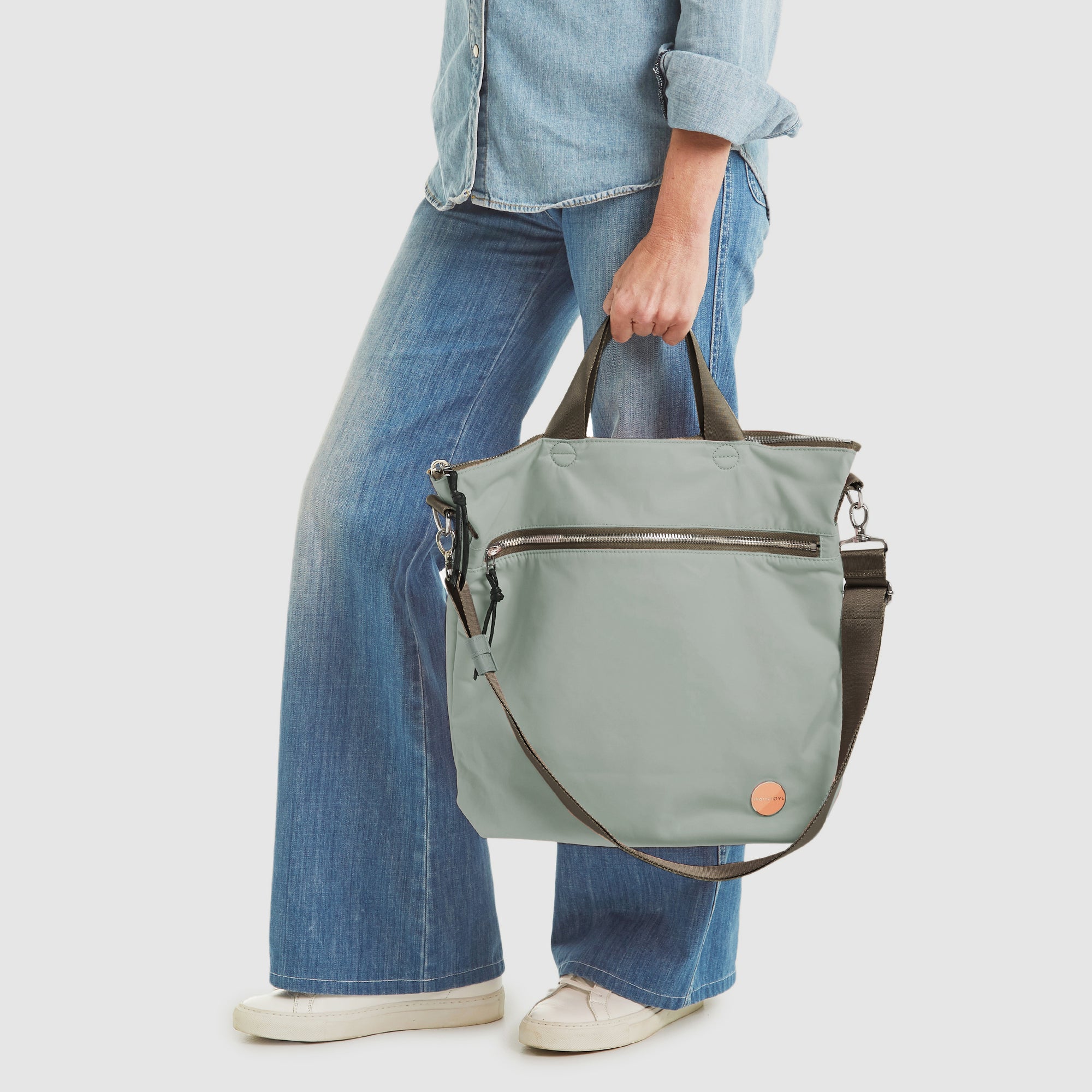 shortyLOVE wonder large crossbody/messenger bag in slate/teal; hand held by model in jeans against white background.