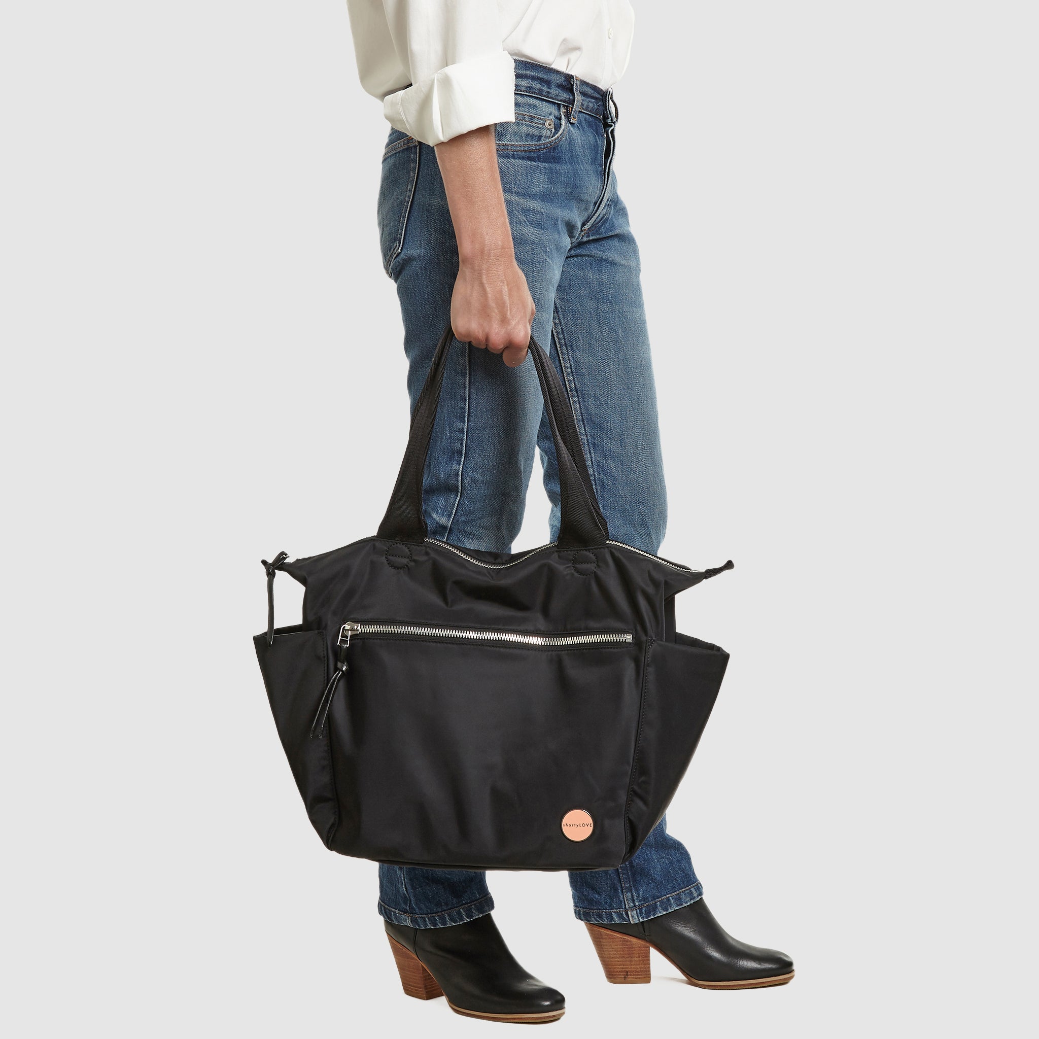 shortyLOVE tillie tote bag in black; held by model in white button down shirt and jeans against white background.