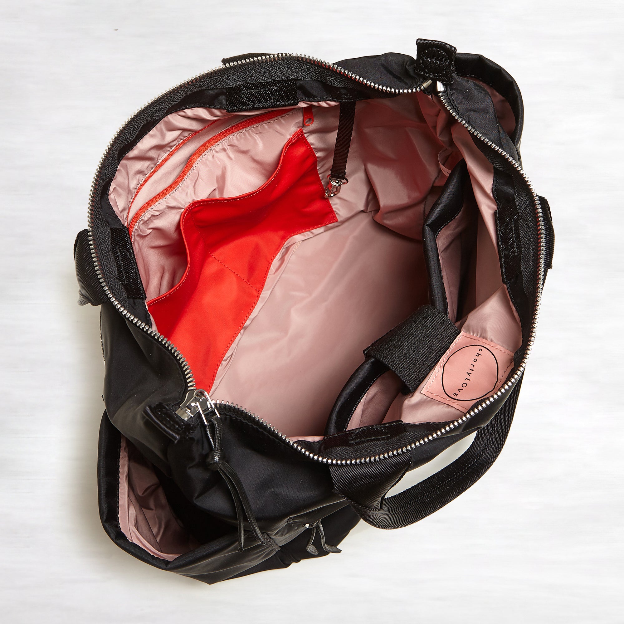 shortyLOVE tillie tote bag in black; top-down view showing interior pink lining against white background.