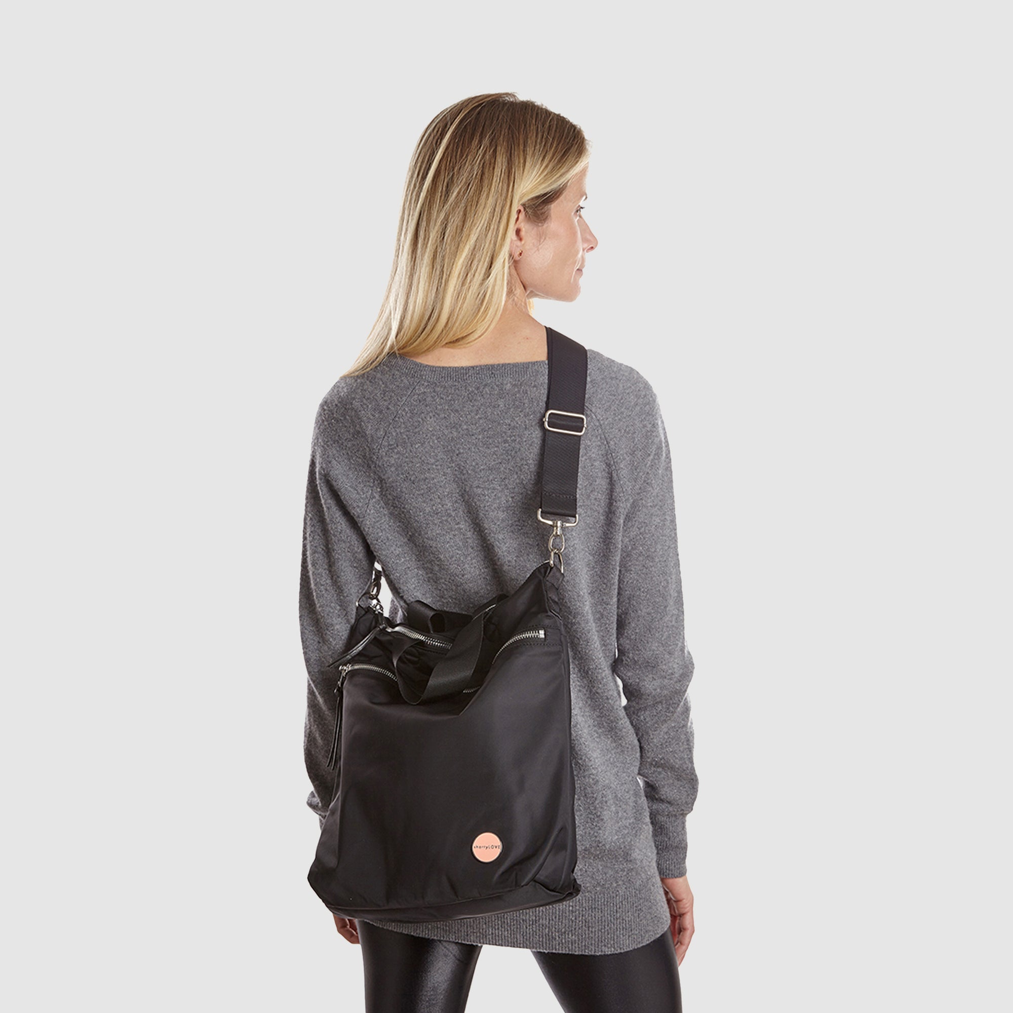shortyLOVE wonder large crossbody/messenger bag in black; on model in grey long sleeve sweater and black leggings against white background.
