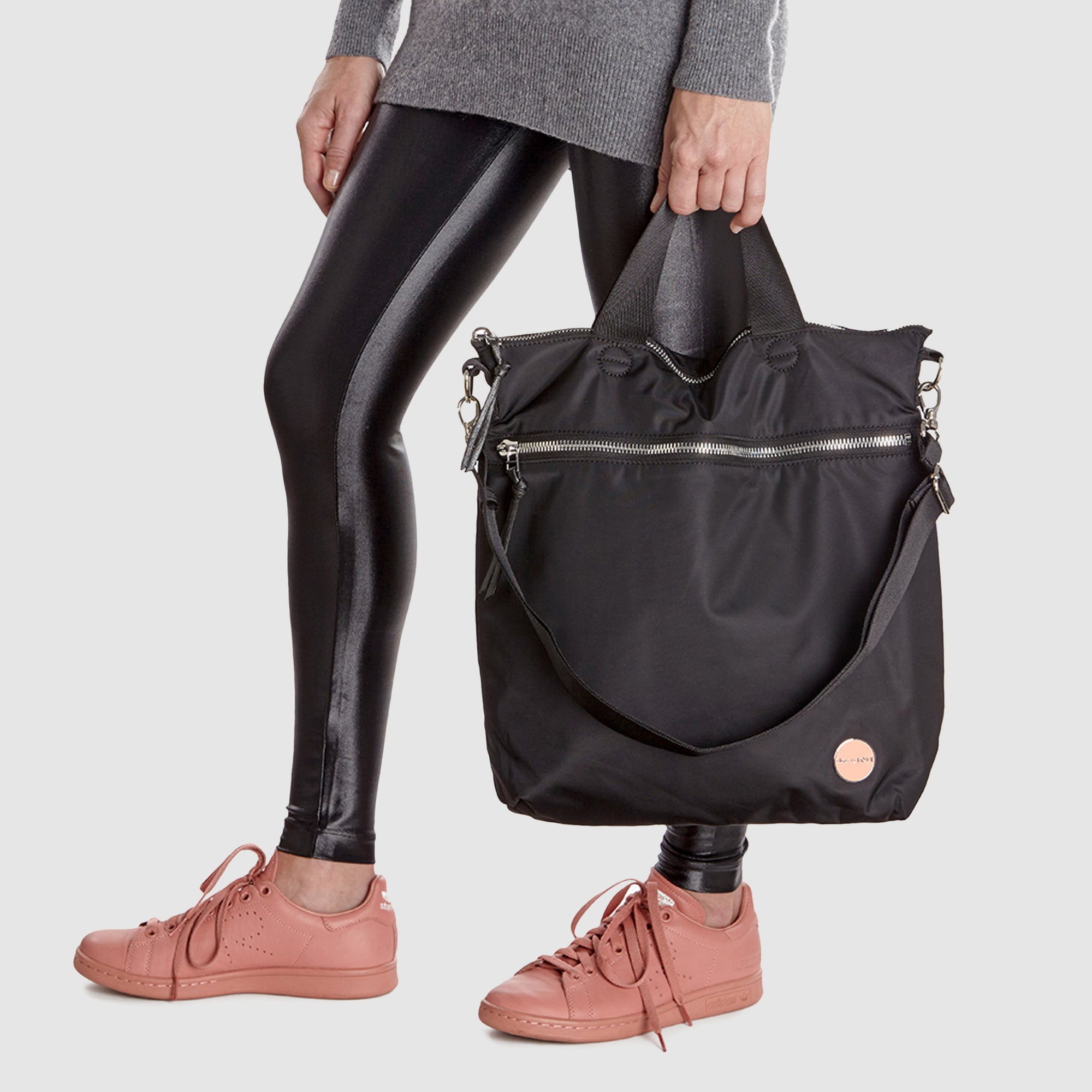 shortyLOVE wonder large crossbody/messenger bag in black; hand held by model in grey long sleeve sweater and black leggings against white background.