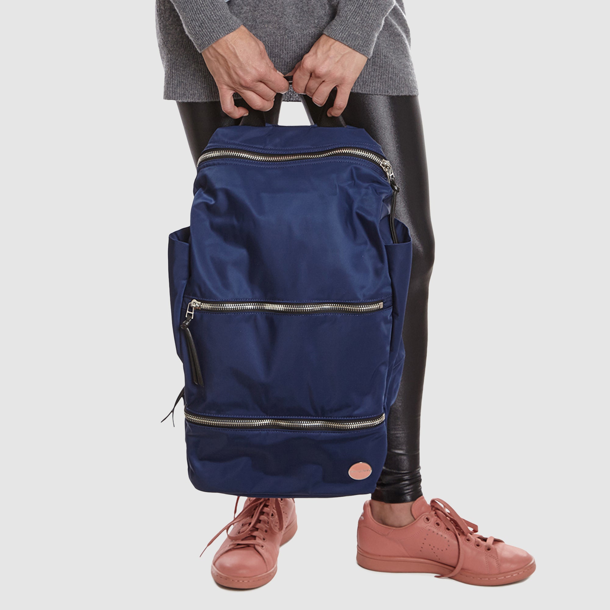 Person holding a navy blue boxer backpack on a plain background