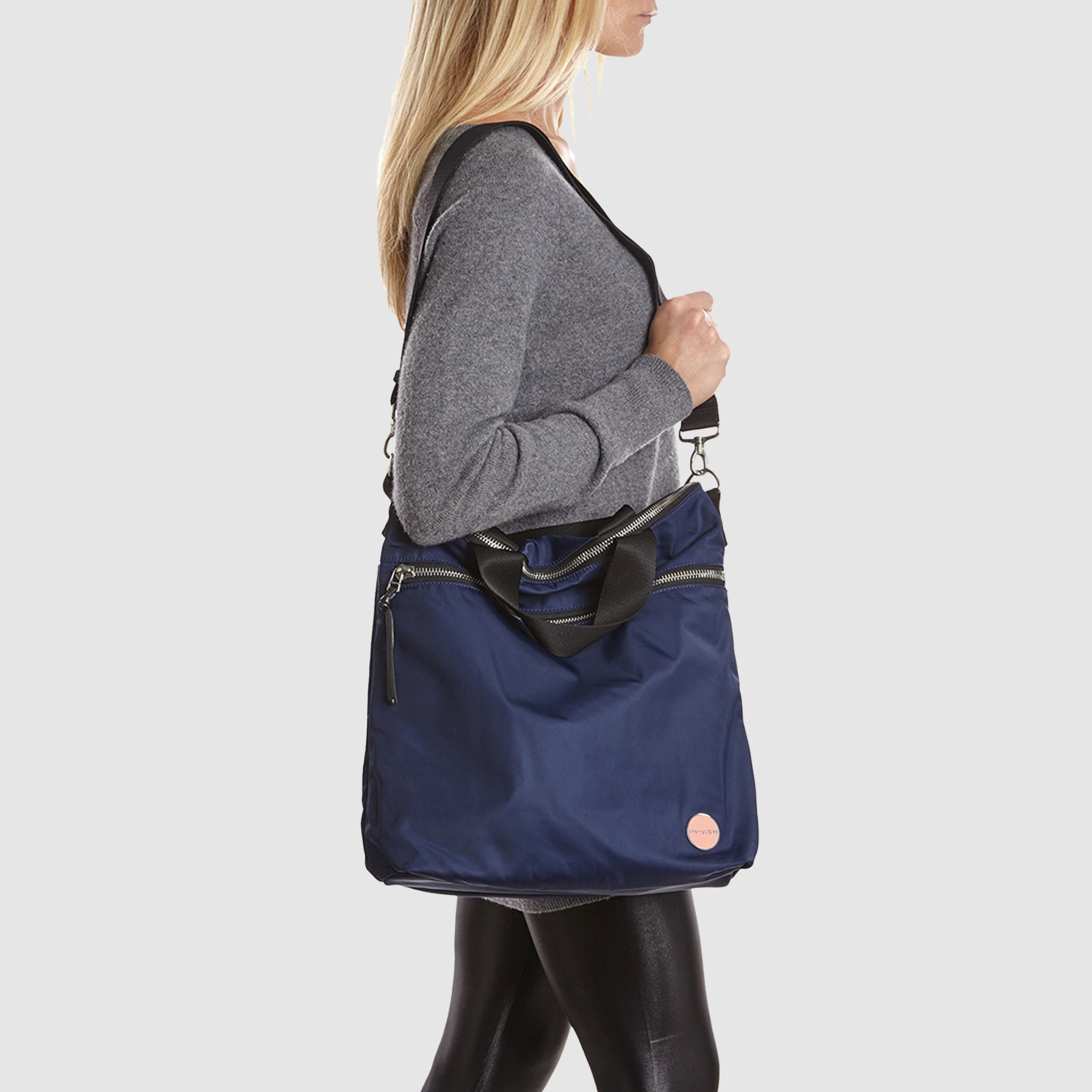 shortyLOVE wonder large crossbody/messenger bag in navy; on model in grey long sleeve sweater and black leggings against white background.