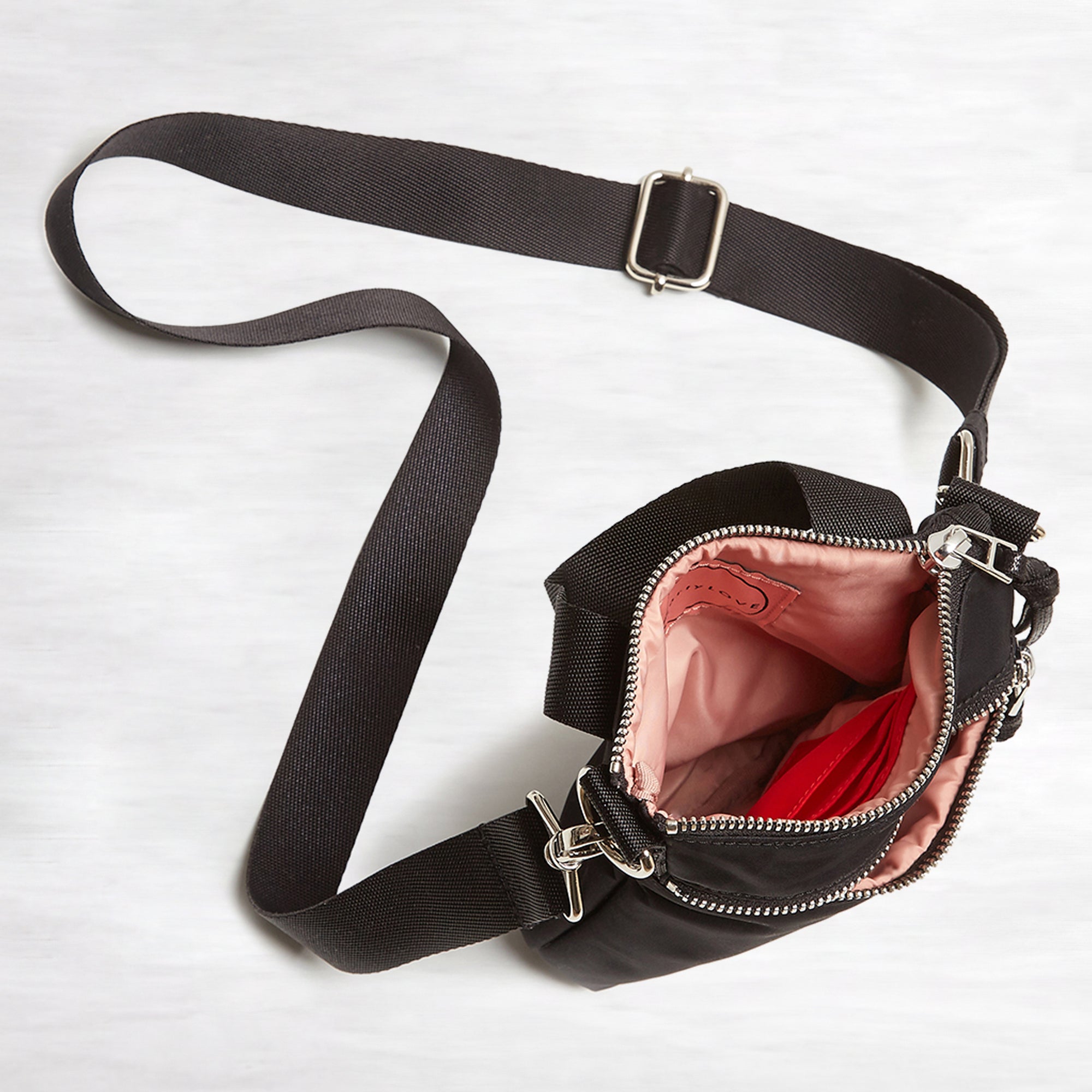 shortyLOVE shorthand crossbody phone bag in black; top-down view showing interior pink lining against white background