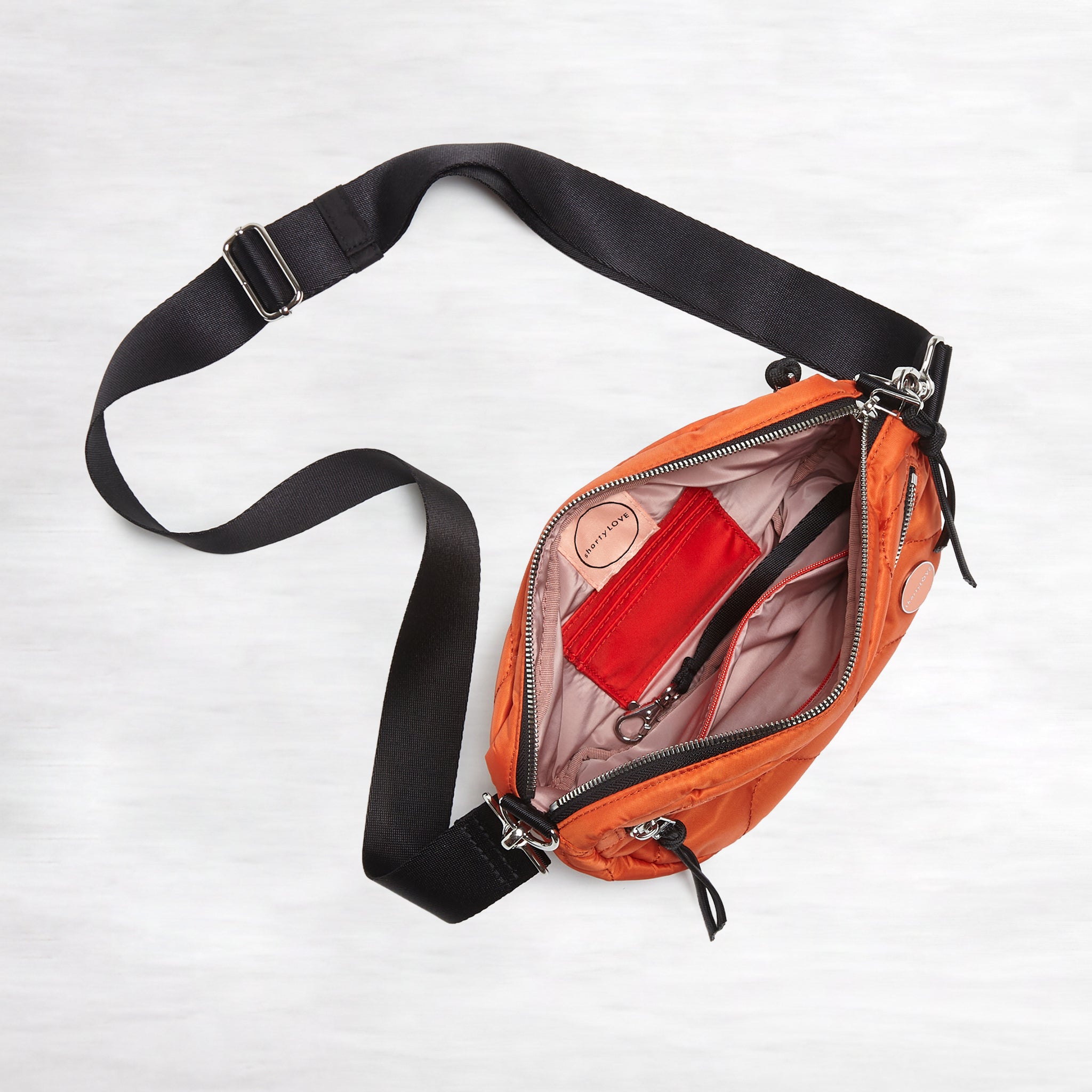 shortyLOVE small cruiser small crossbody bag in orange; top-down view showing interior blush lining against white background.