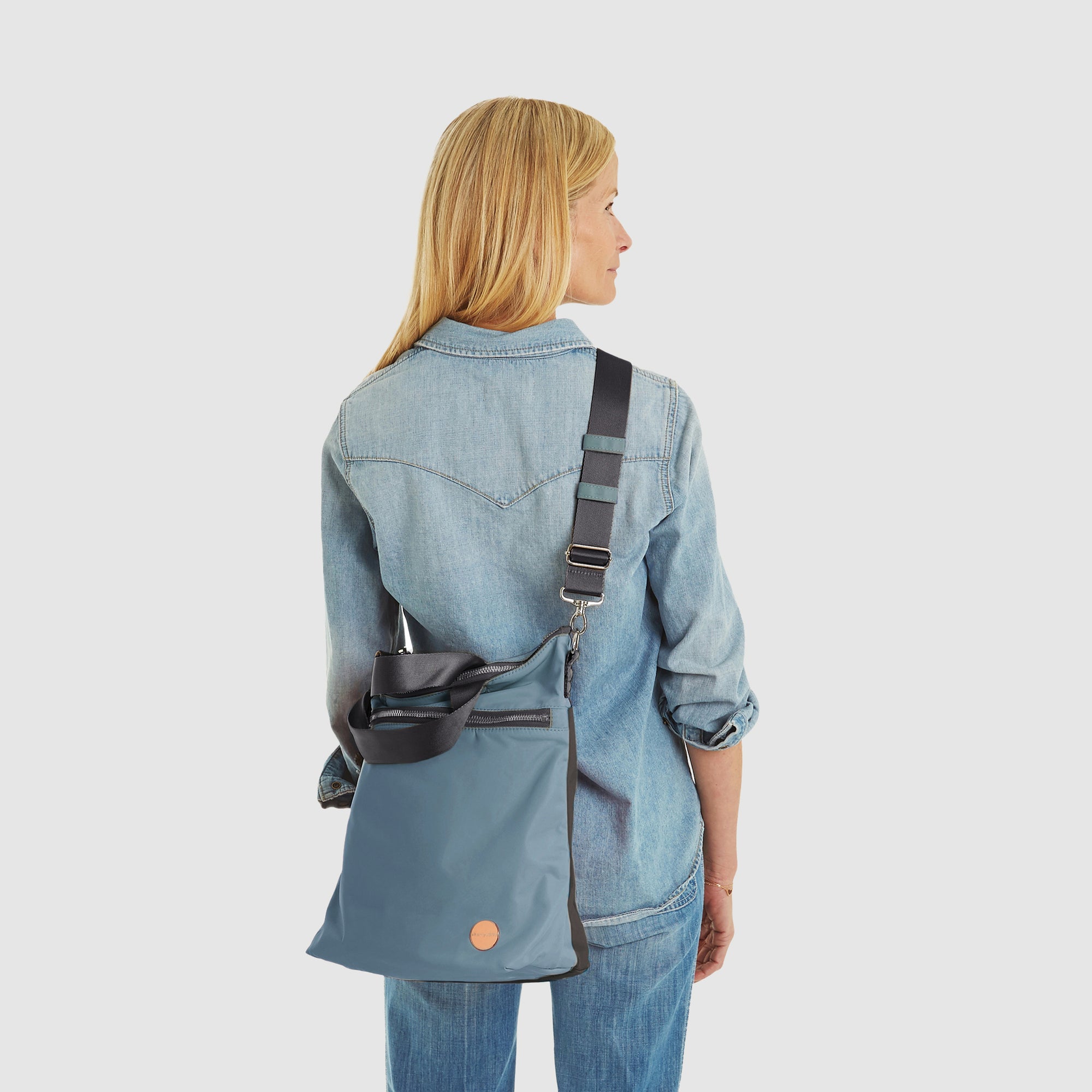 shortyLOVE wonder large crossbody/messenger bag in steel blue/charcoal; worn crossbody by model in jeans against white background.