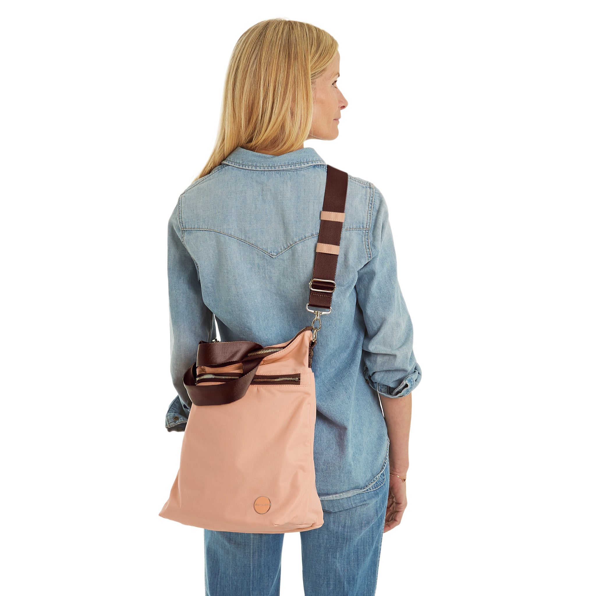 shortyLOVE wonder large crossbody/messenger bag in dusty peach; on model in jean top and jeans against white background.