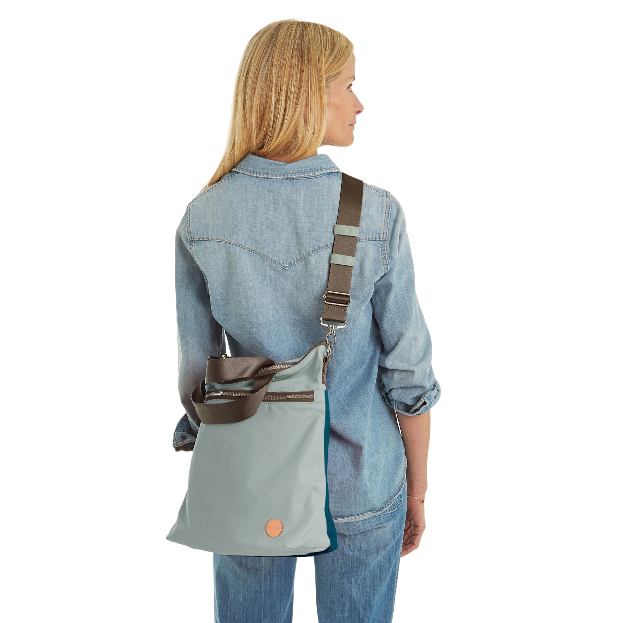 shortyLOVE wonder large crossbody/messenger bag in slate/teal; on model in jean shirt and jeans against white background.