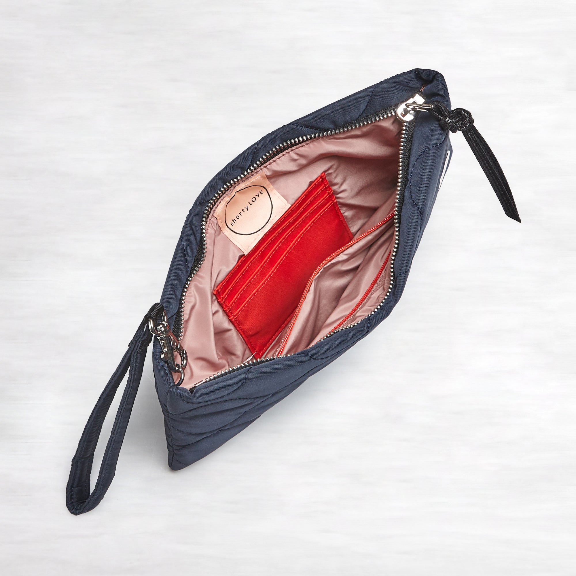 shortyLOVE cleo wristlet clutch in midnight; top-down view showing interior blush lining against white background.