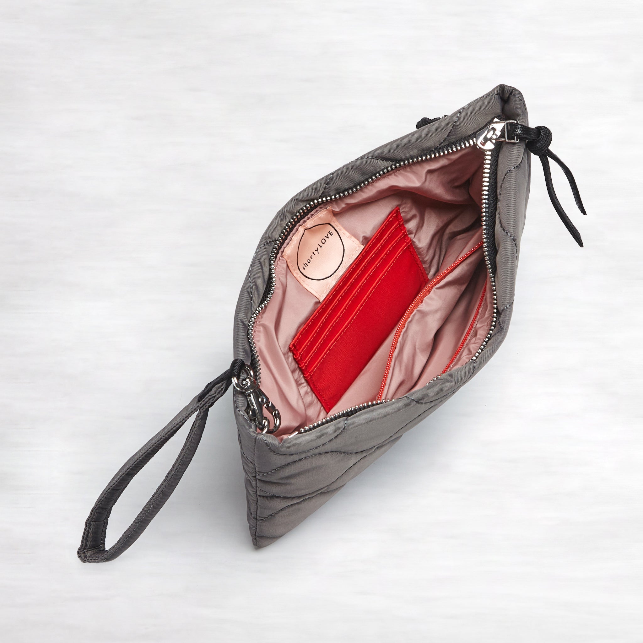 shortyLOVE cleo wristlet clutch in pewter; top-down view showing interior blush lining against white background.