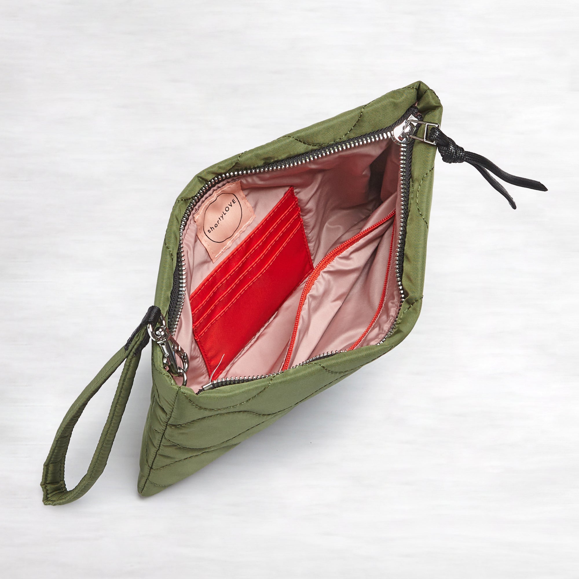 shortyLOVE cleo wristlet clutch in sage; top-down view showing interior blush lining against white background.