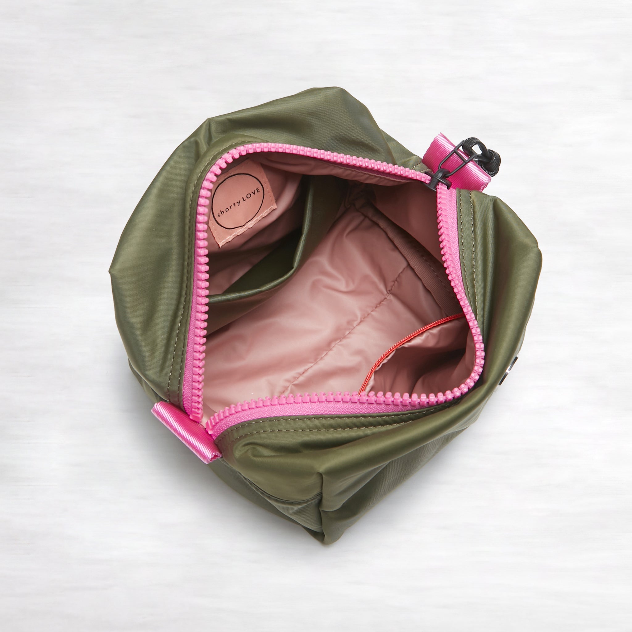shortyLOVE stevie cosmetic bag in army green; top-down view showing interior pink lining against white background.