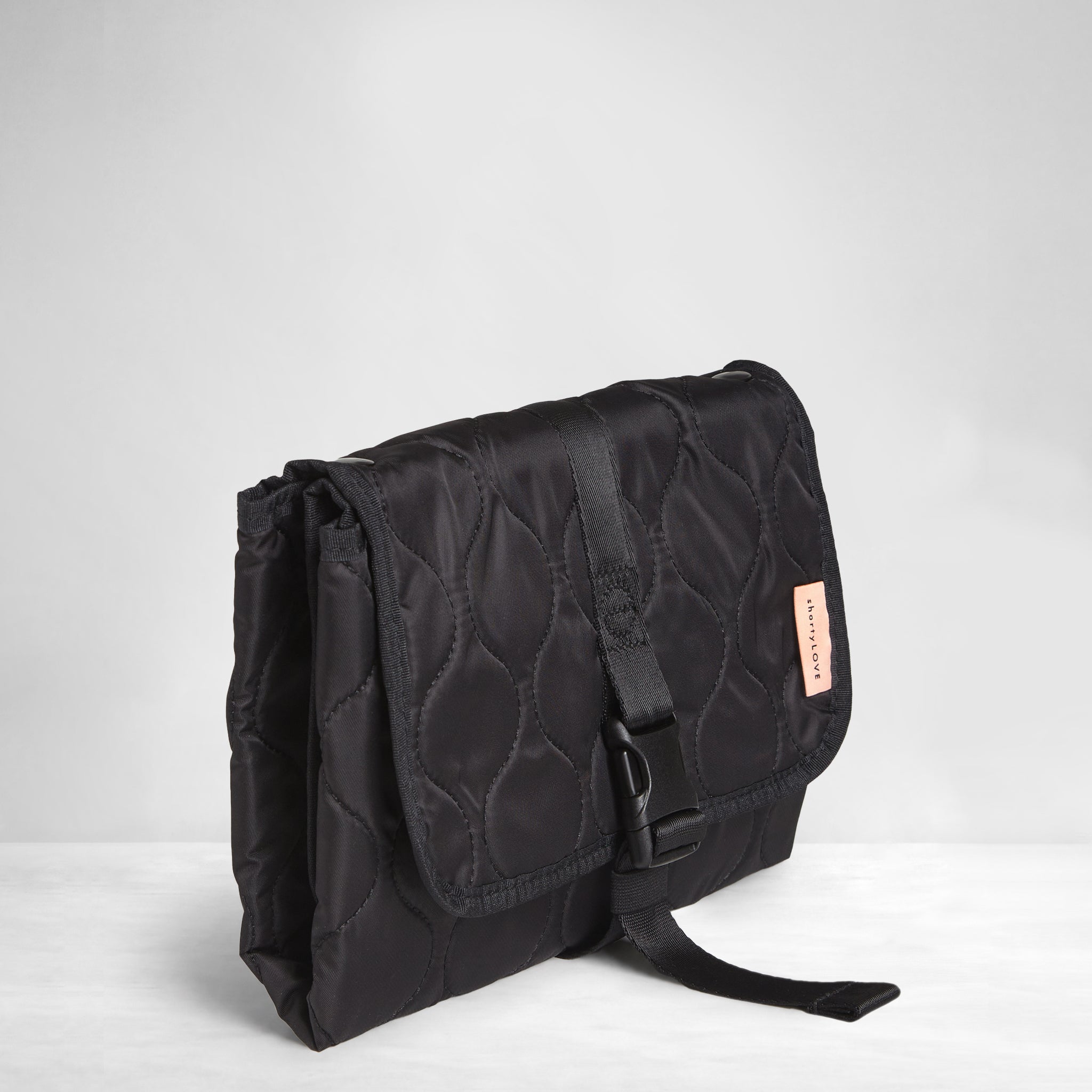 Black quilted diaper changing mat folded and closed - side view on a white background