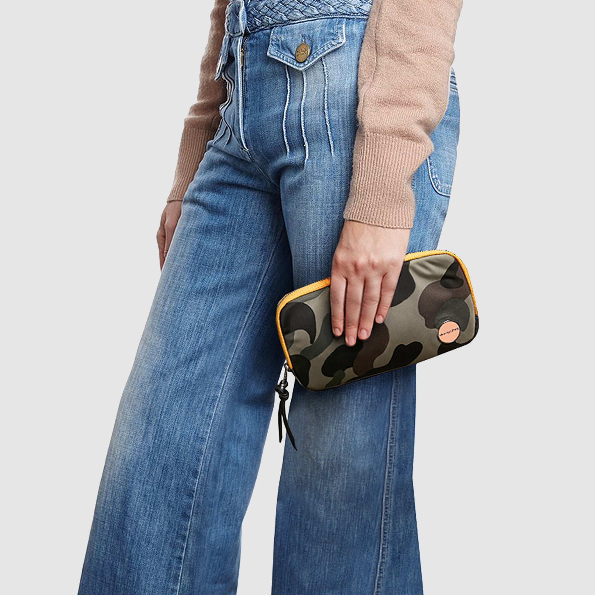 shortyLOVE jetty clutch/wallet in green camo; hand held by model in black sweatshirt and jeans against white background.