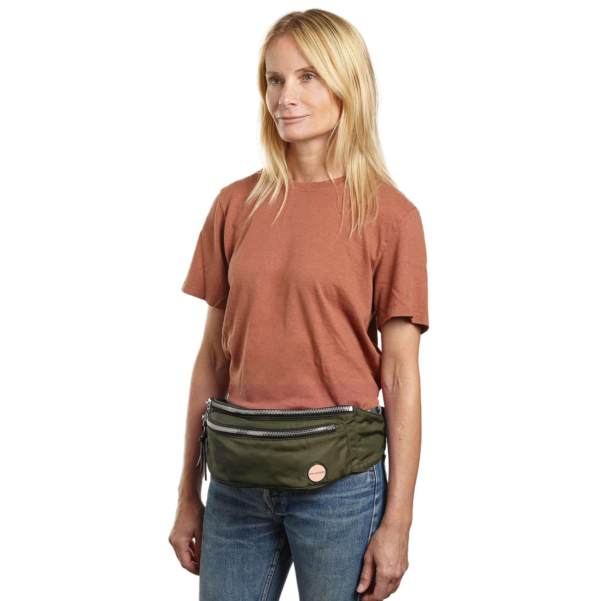 shortyLOVE arcade belt bag in army green; on model in rust t-shirt and jeans against white background.