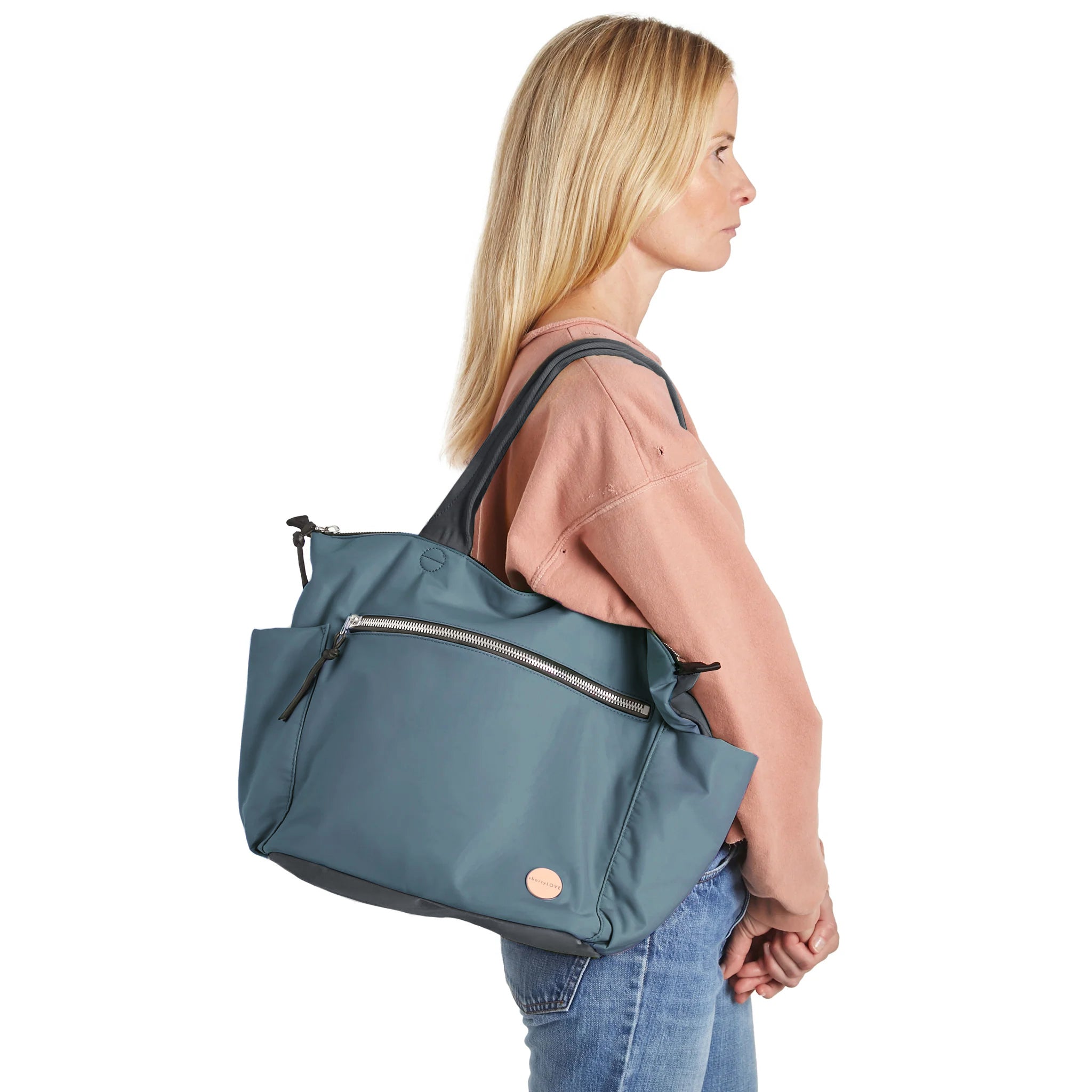 shortyLOVE tillie tote bag in steel blue/charcoal; on model in peach sweatshirt and jeans against white background.