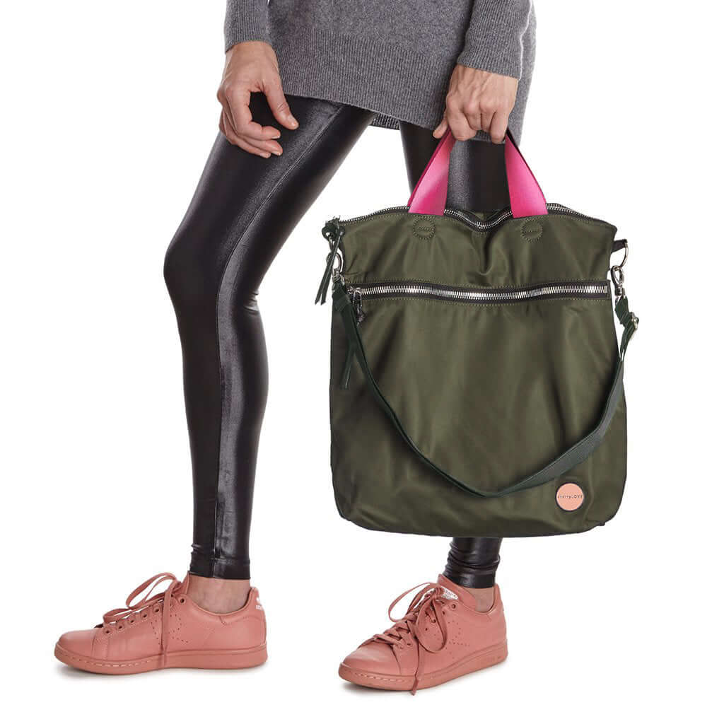 shortyLOVE wonder large crossbody/messenger bag in army green; hand held by model in grey long sleeve sweater and black leggings against white background.