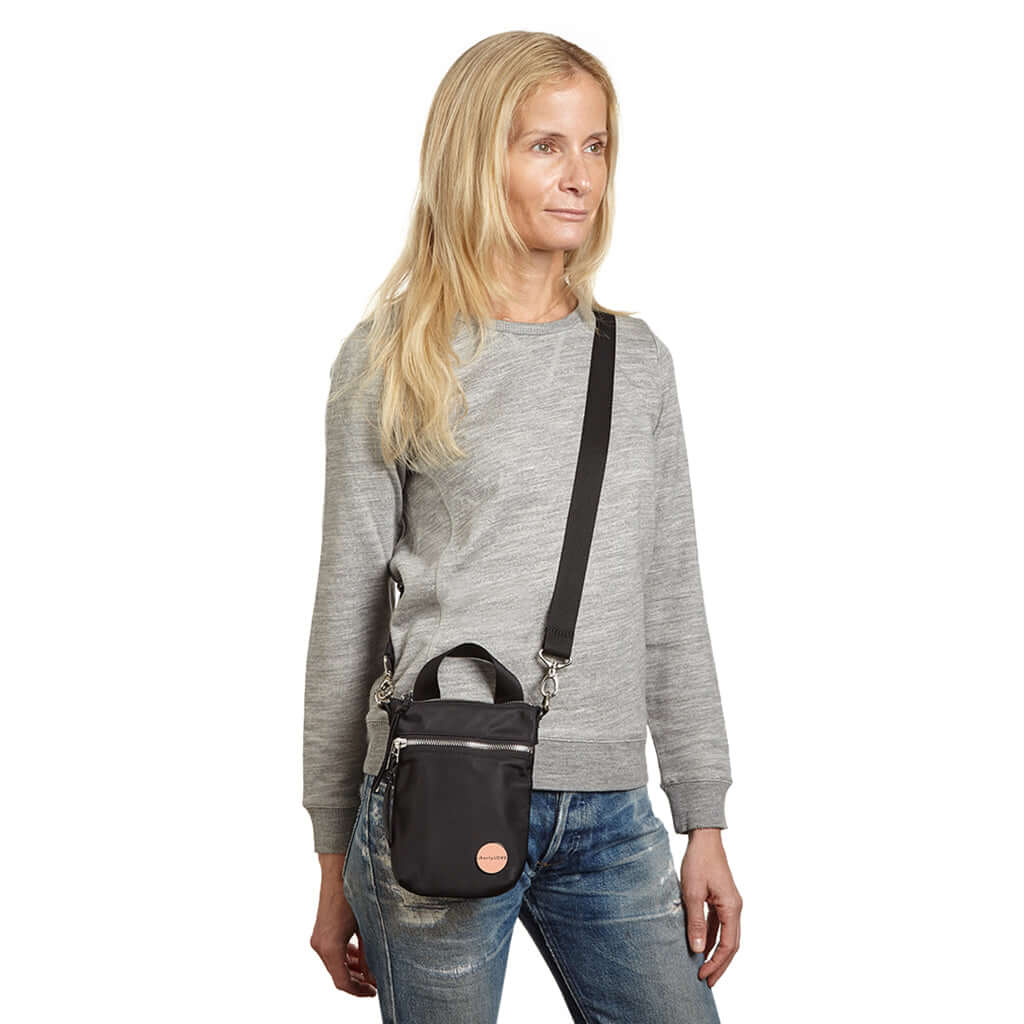 shortyLOVE shorthand crossbody phone bag in black; on model in grey sweatshirt and jeans against white background