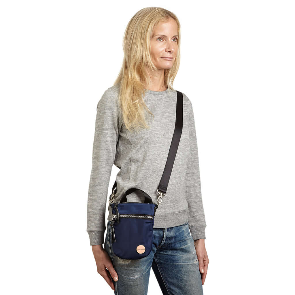 shortyLOVE shorthand crossbody phone bag in navy; on model in grey sweatshirt and jeans against white background.