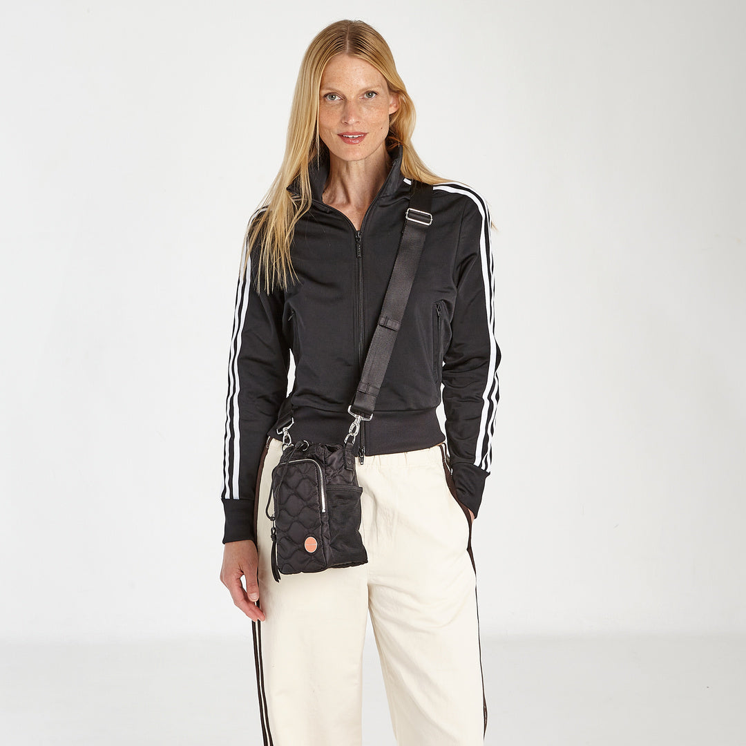 shortyLOVE bea sling bag in black; on model in black top against grey background.